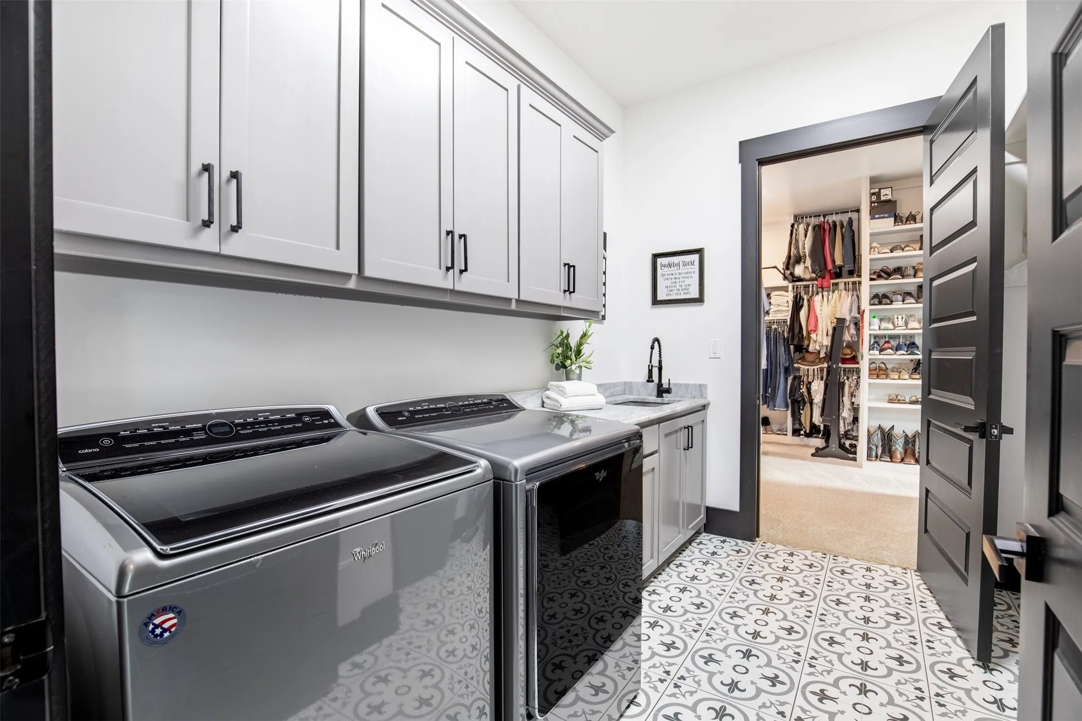 Stylish downstairs laundry room connects to primary closet and provides ample cabinetry and utility sink