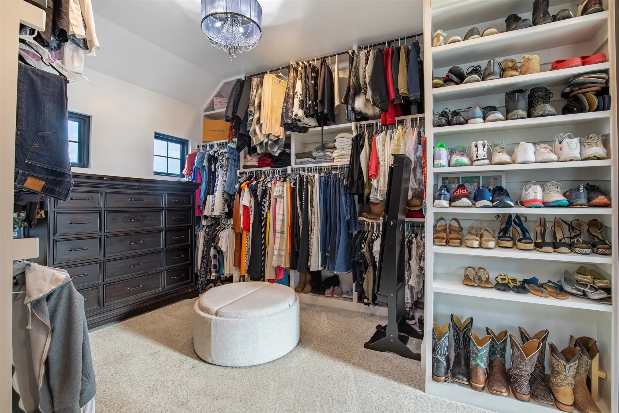Custom closet featuring extensive built-in shelving, multiple hanging rods with pull downs, and custom shoe racks