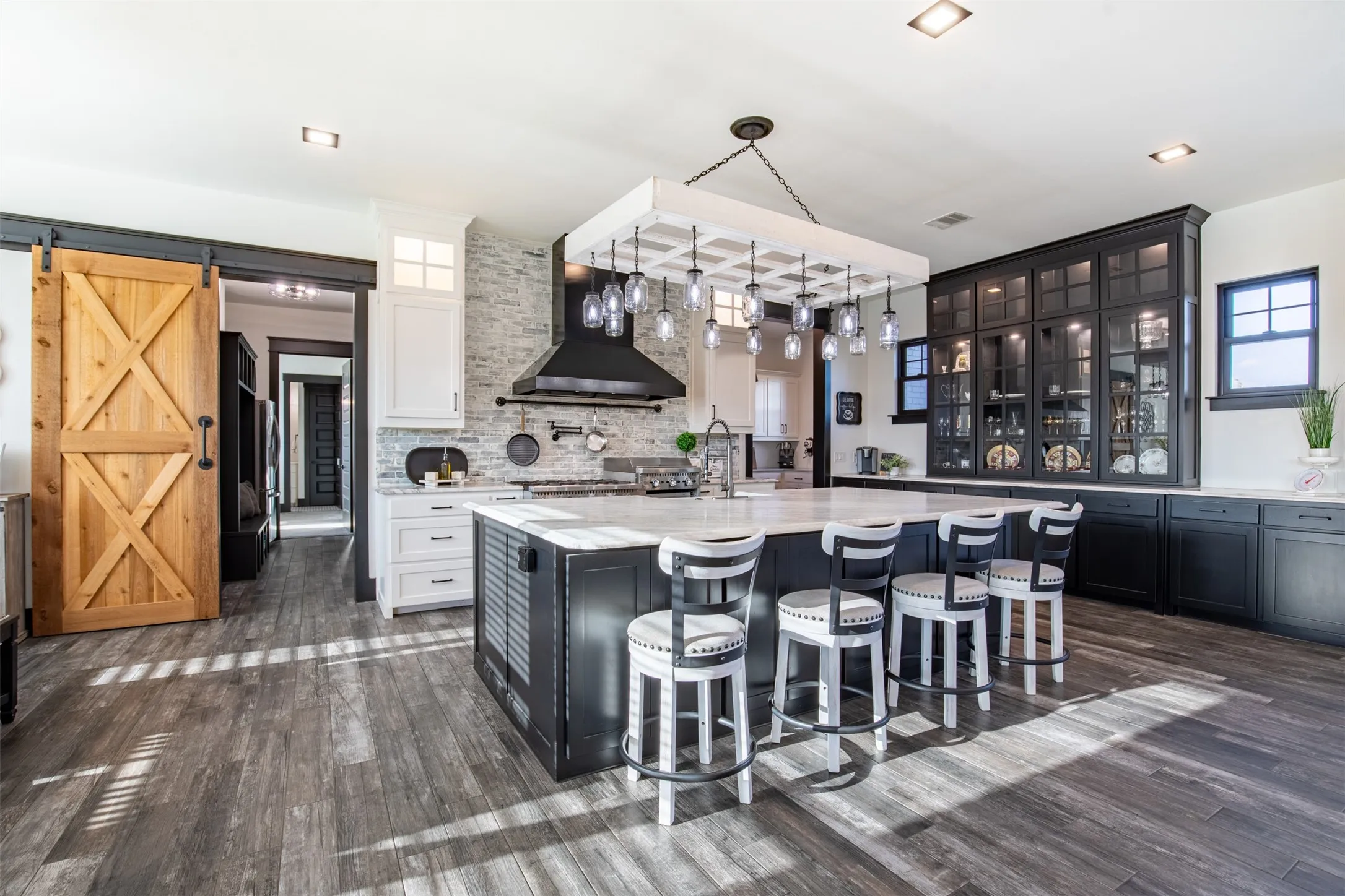 Striking modern farmhouse kitchen with elegant built-in dining hutch, brick backsplash with white cabinetry and Brazilian marble countertops