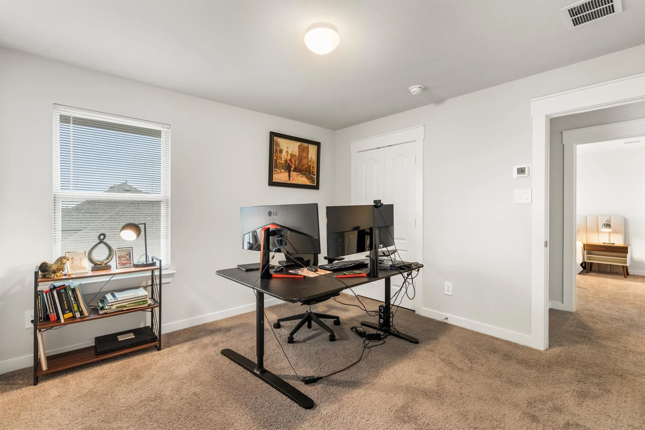 Carpeted room with a ceiling-mounted light fixture, white trim, and a window with blinds