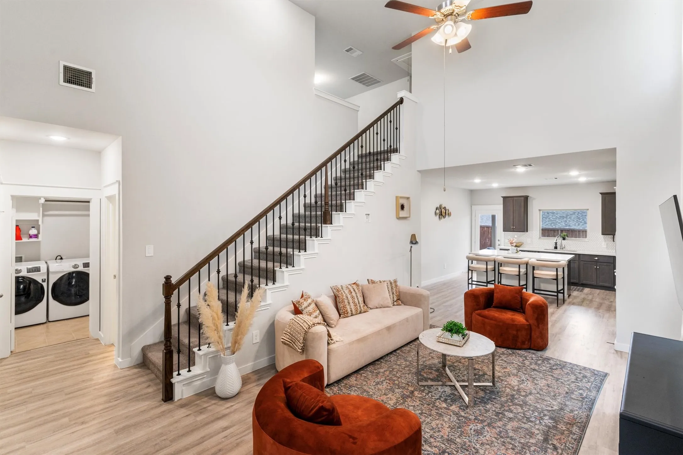 Open-concept living space featuring wood-finish flooring, a two-story ceiling, and a ceiling fan