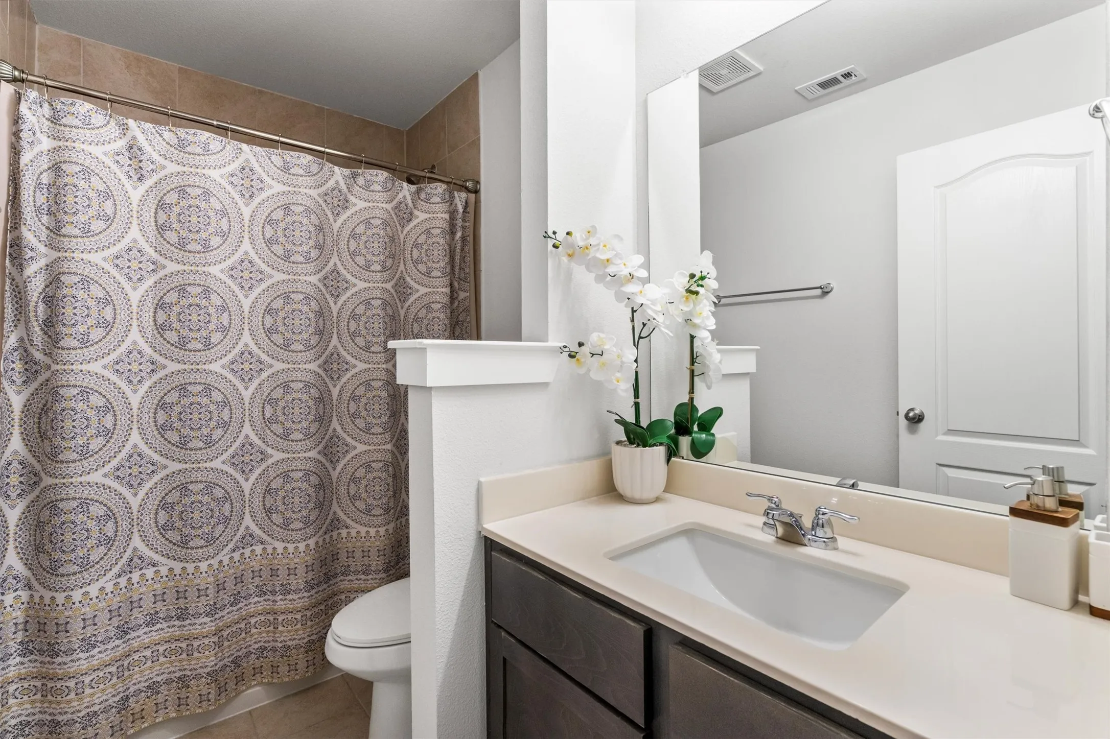 Bathroom with an integrated sink, light-toned countertop, dark wood-finish cabinetry, and a full-width mirror