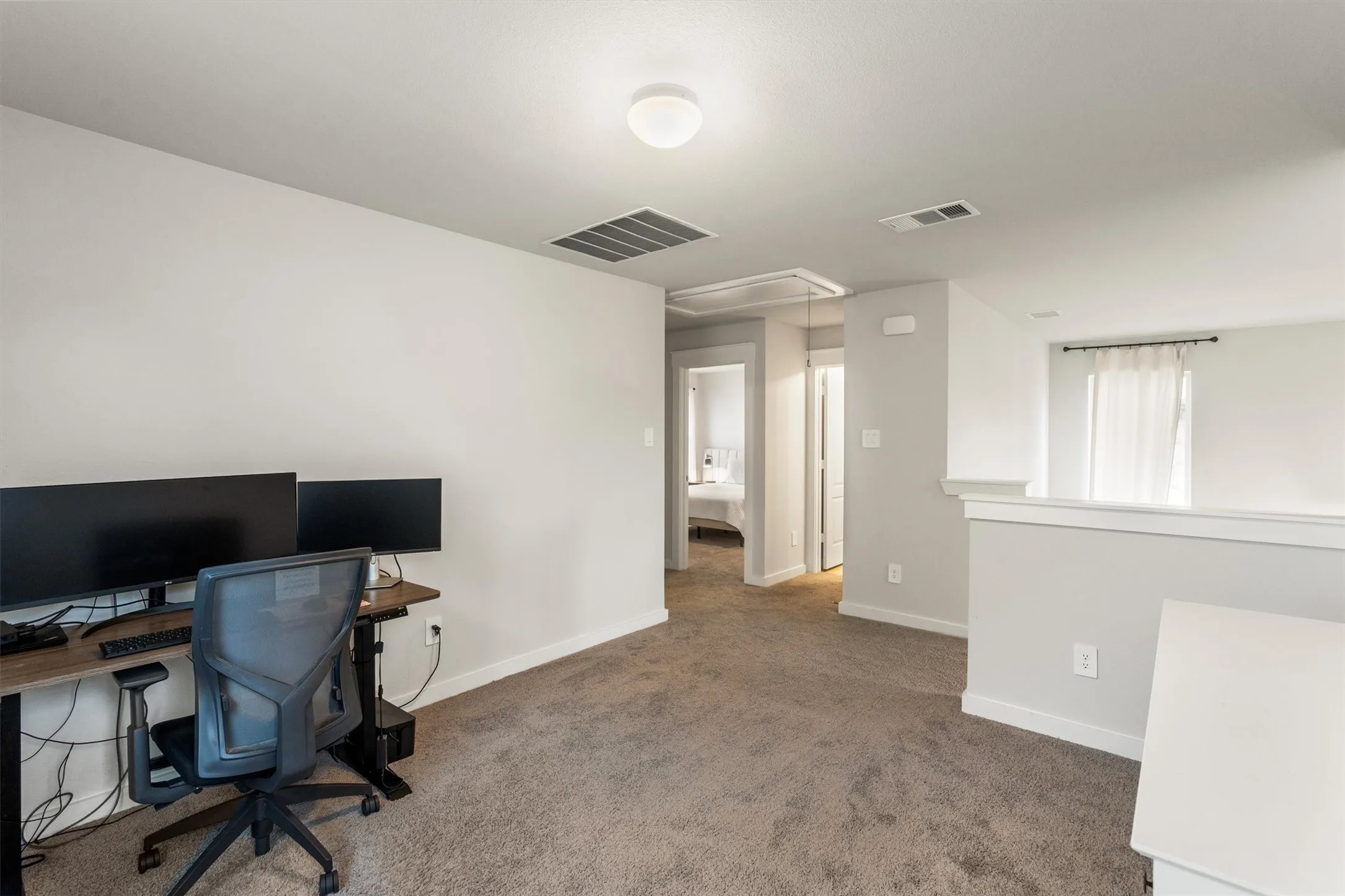 Carpeted loft space featuring light neutral wall tones, white trim, a flush mount ceiling light, and a half-wall railing