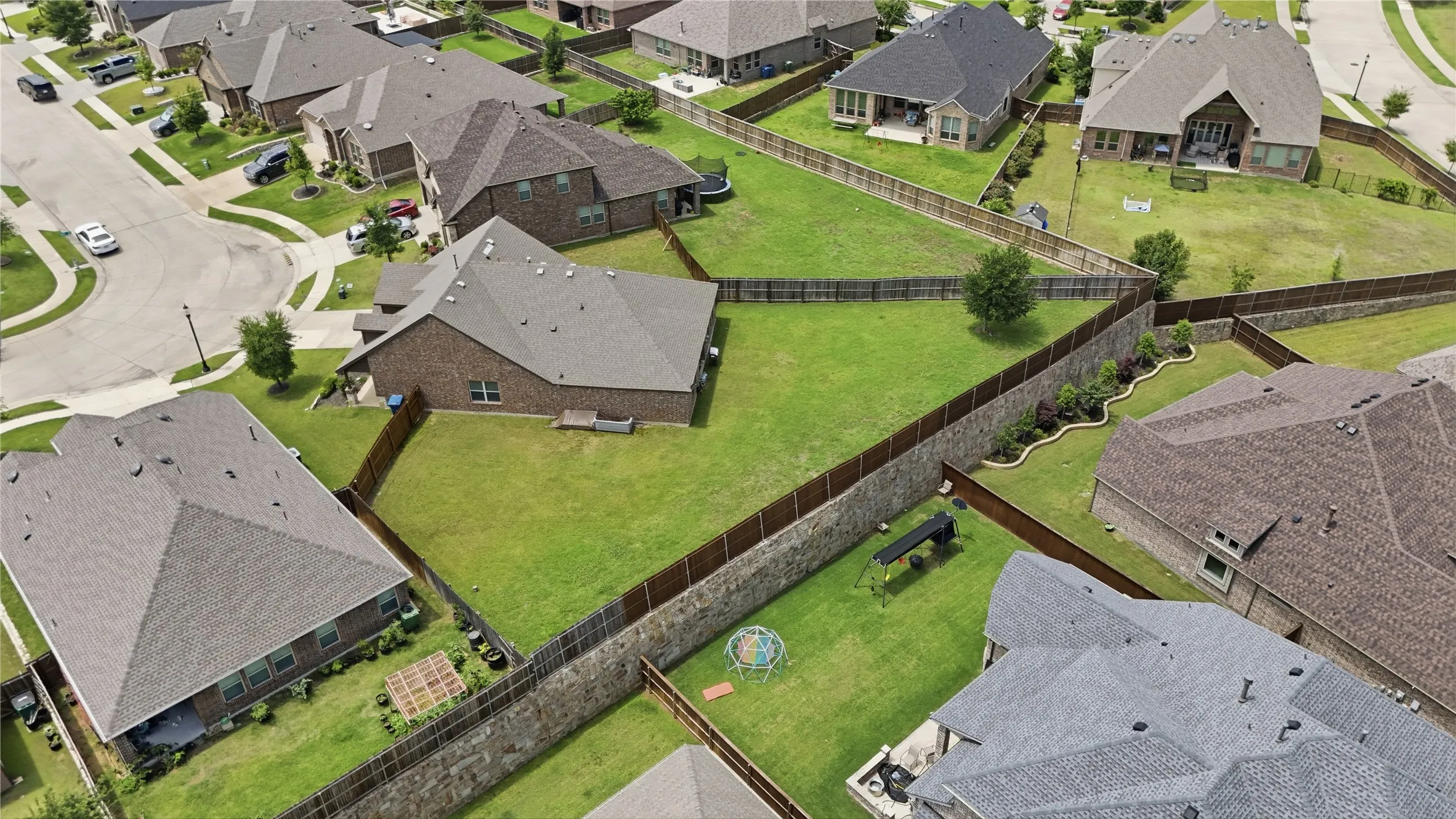 Expansive backyard featuring a manicured lawn, surrounding privacy fencing, and established landscaping