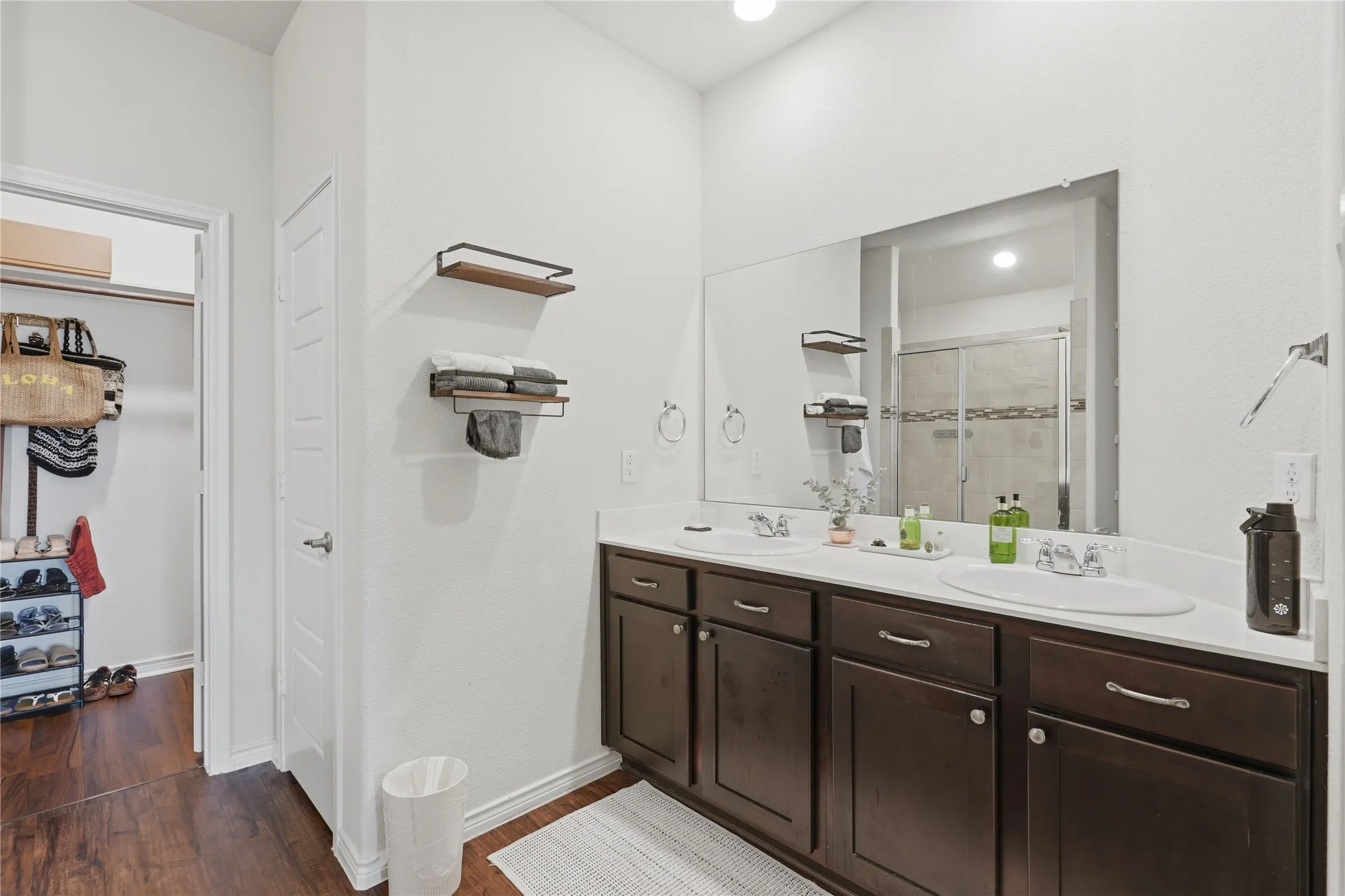 Double vanity featuring wood-finish cabinetry and a single large mirror