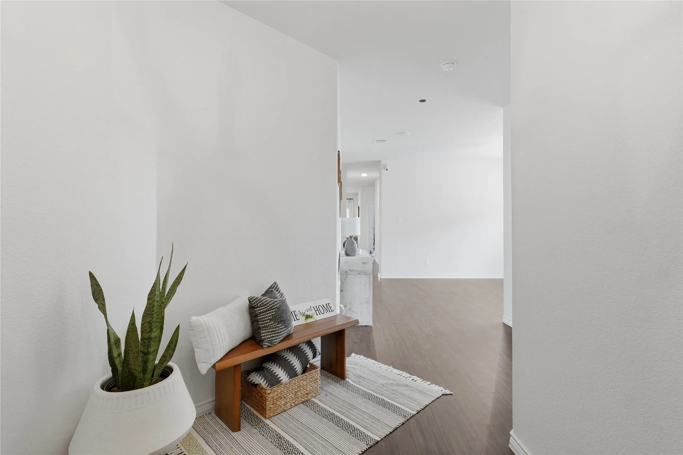 Bright interior hallway featuring light-toned walls and wood-finish flooring