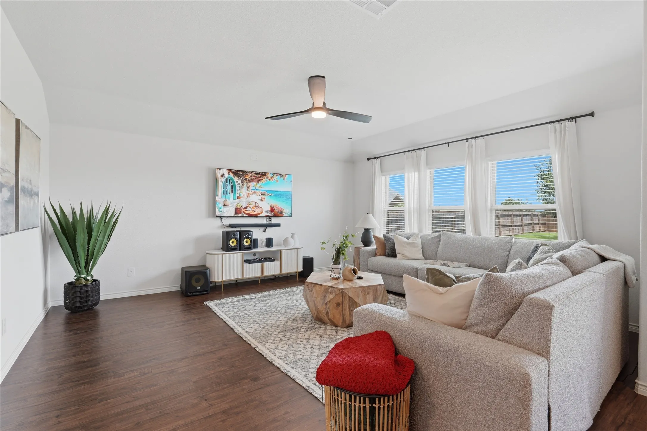 Living area with dark wood-finish flooring and a contemporary ceiling fan