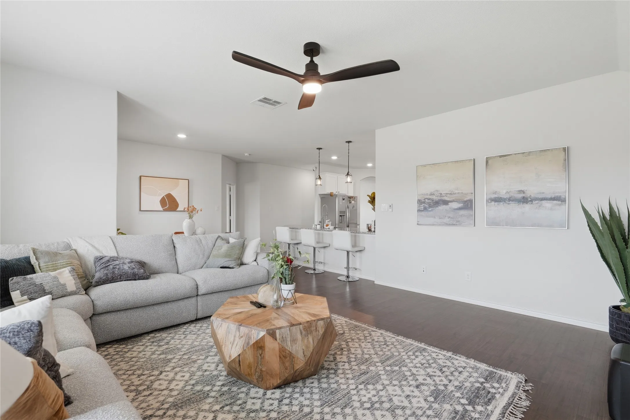 Spacious living area with dark wood-finish flooring, recessed lighting, and a contemporary ceiling fan