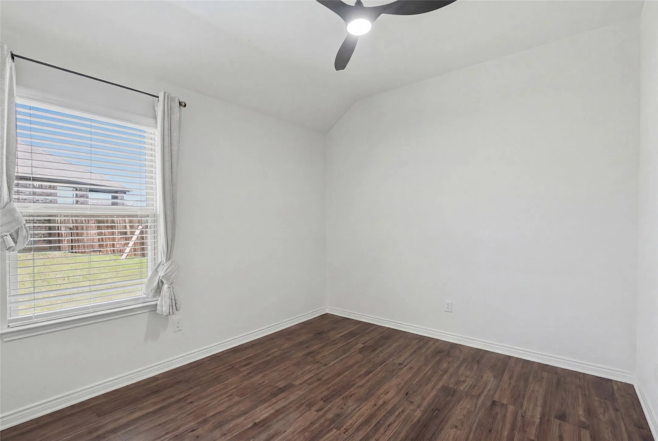Bright interior space featuring wood-finish flooring, white baseboards, and a modern ceiling fan