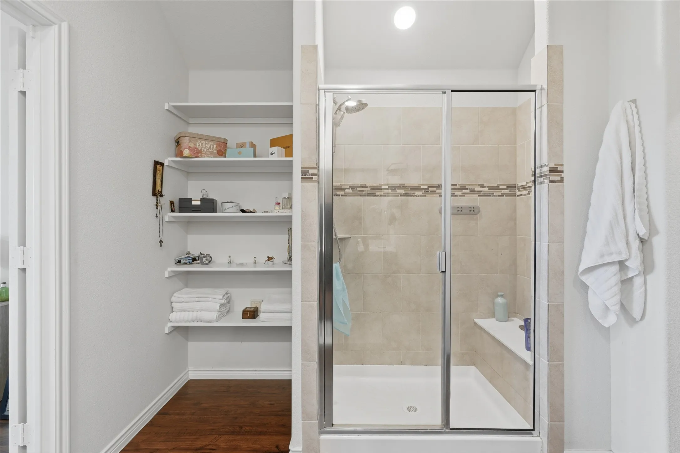 Glass-enclosed shower with tiled walls and a built-in bench