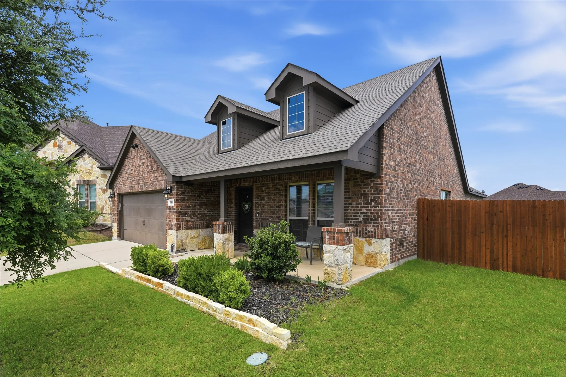 Brick and stone veneer exterior featuring a covered front porch with stone-clad columns