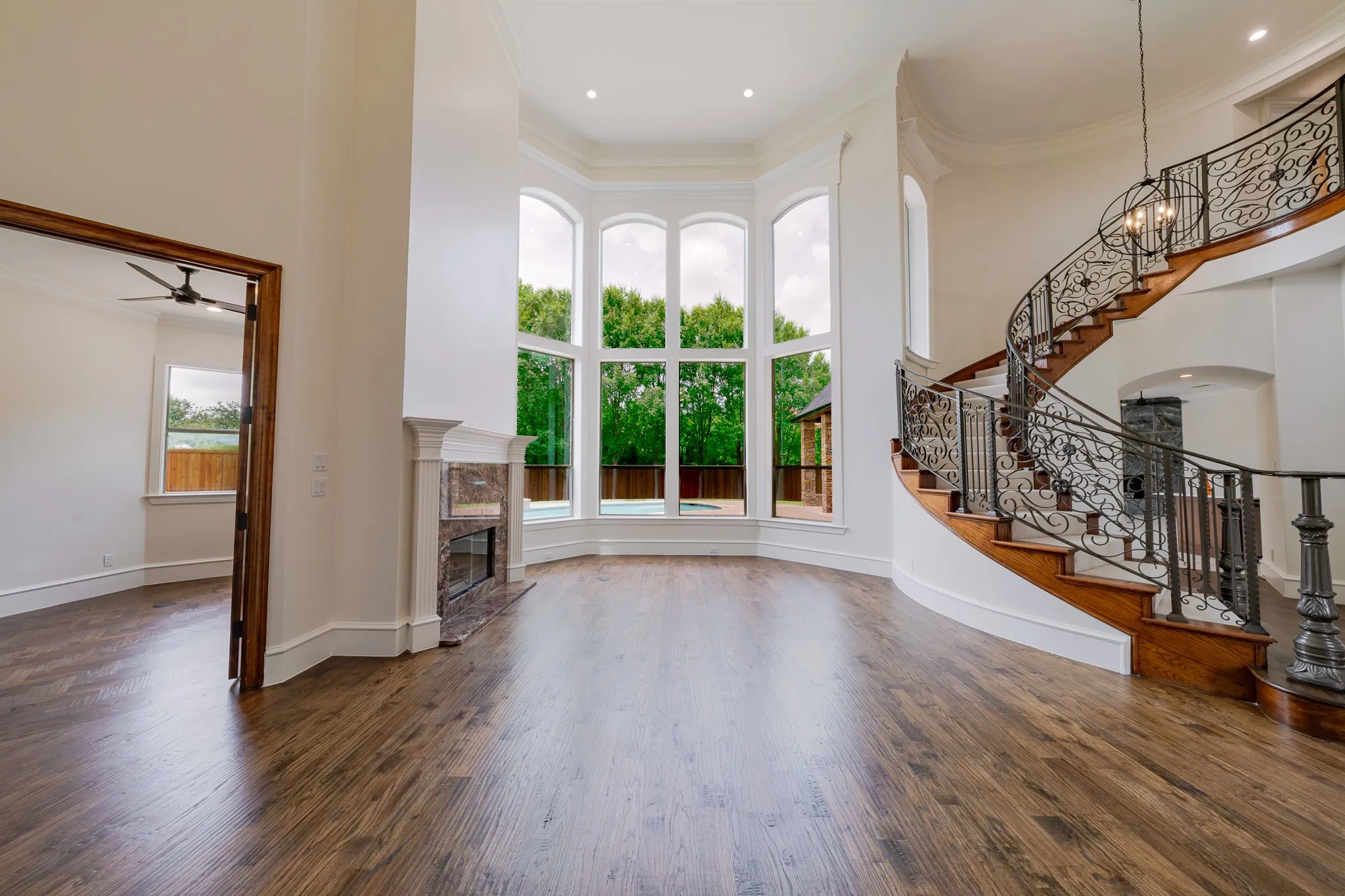 Gracious foyer featuring a curved staircase with wrought iron balusters and wood treads