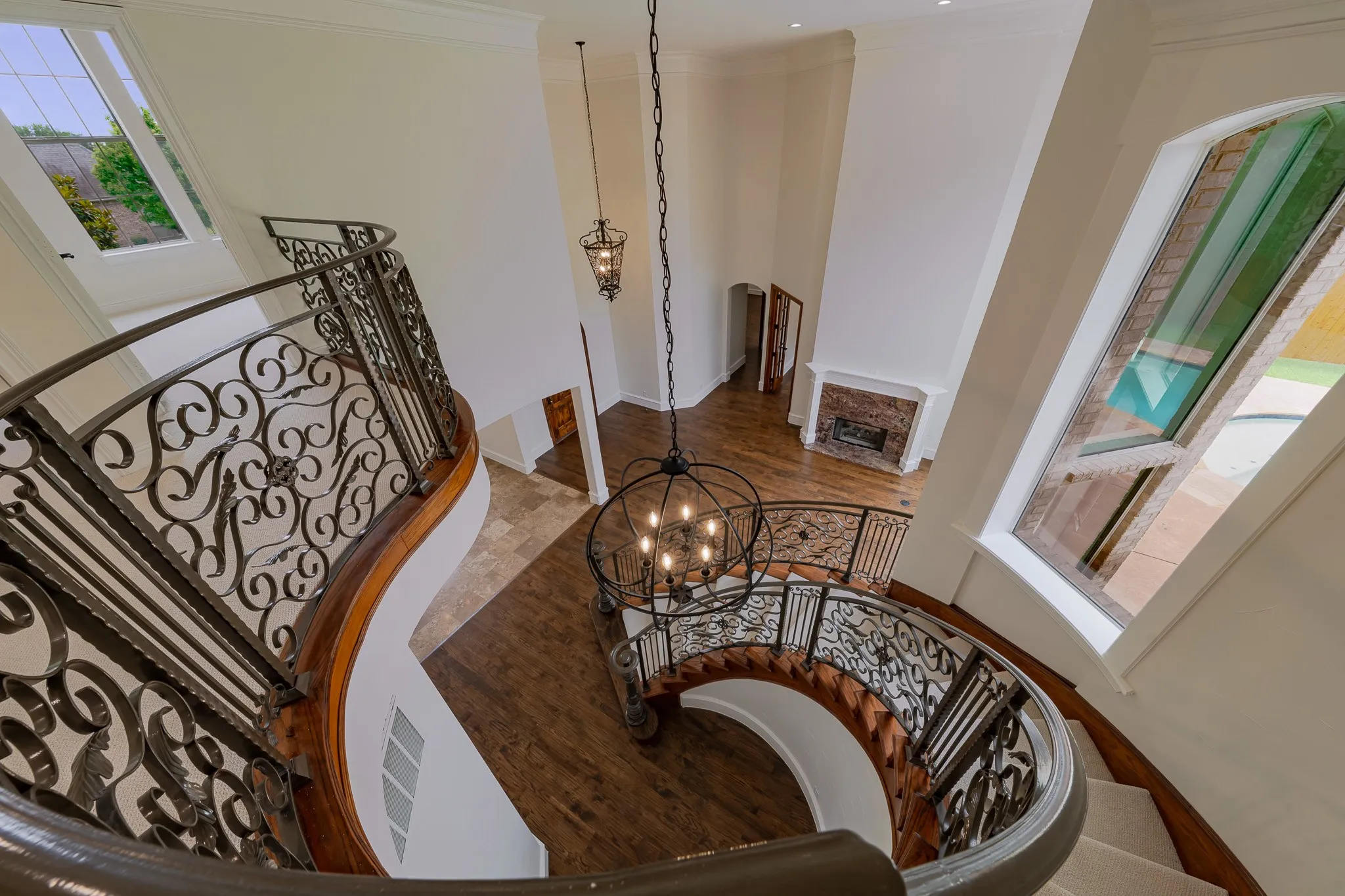 Grand two-story foyer featuring a curved staircase with ornate wrought iron balusters and a wood handrail