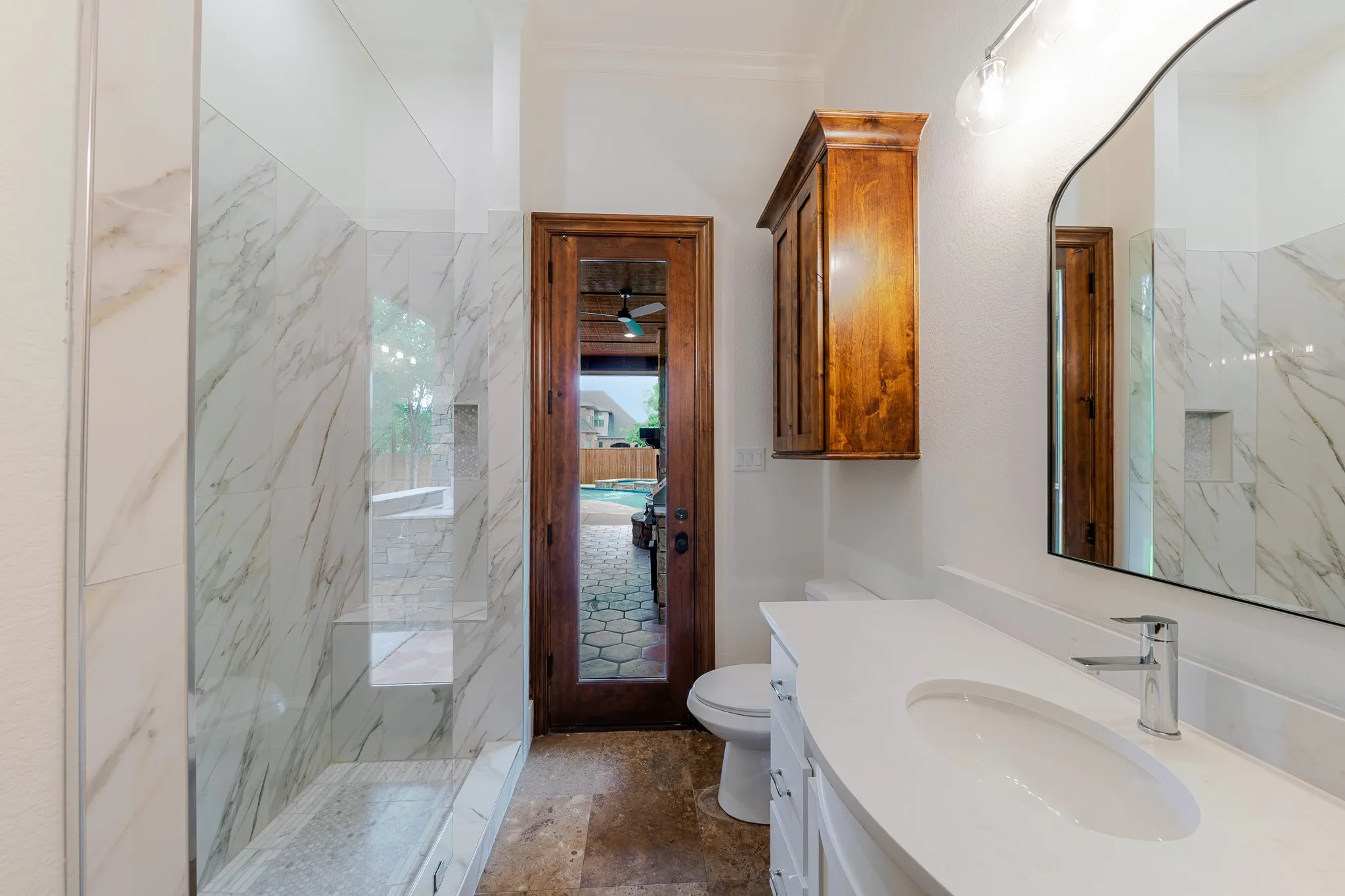 Pool bath featuring a large walk-in shower with bench seating and white marble-look tile