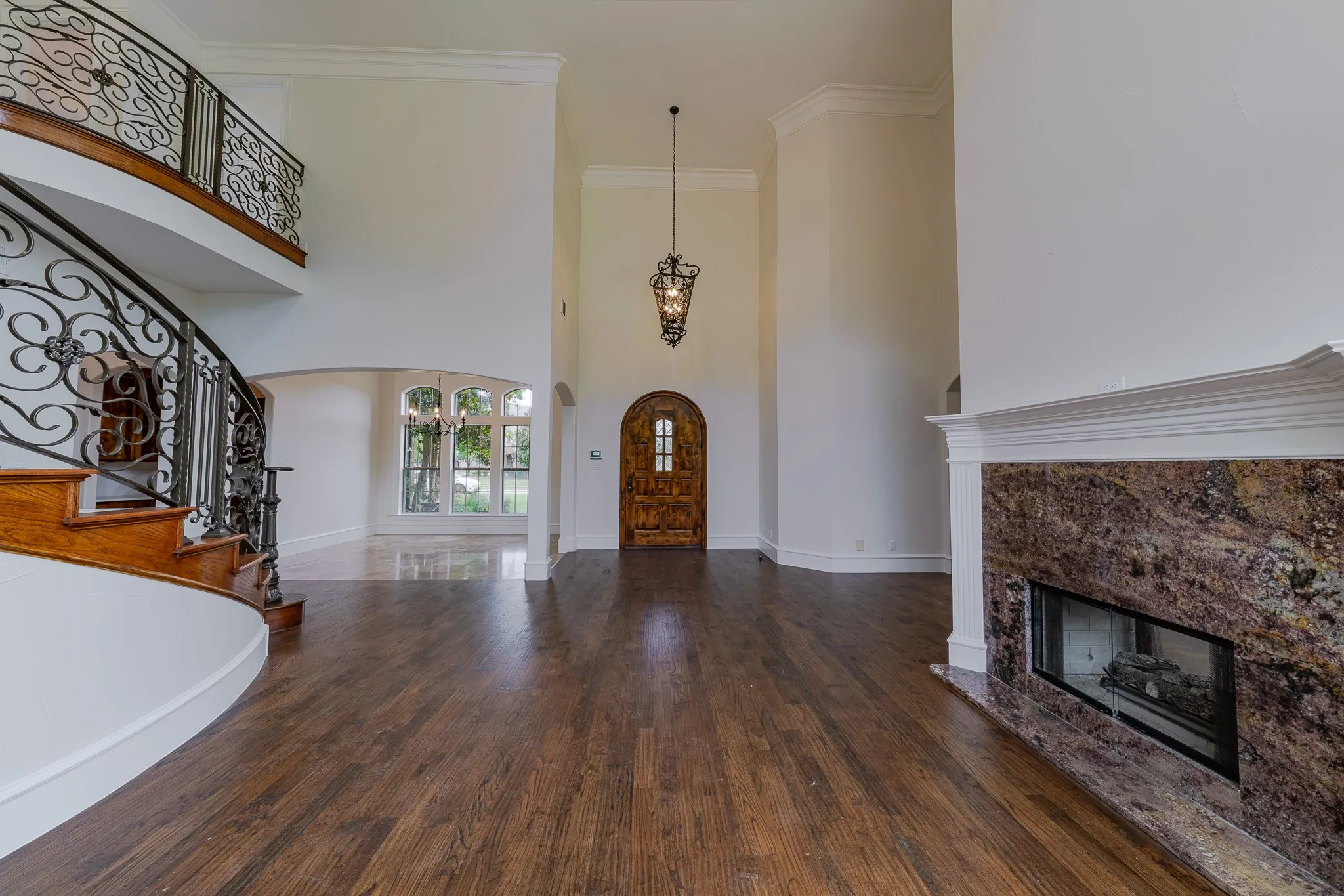 Grand foyer featuring wood-finish flooring and a curved staircase with wrought iron balusters