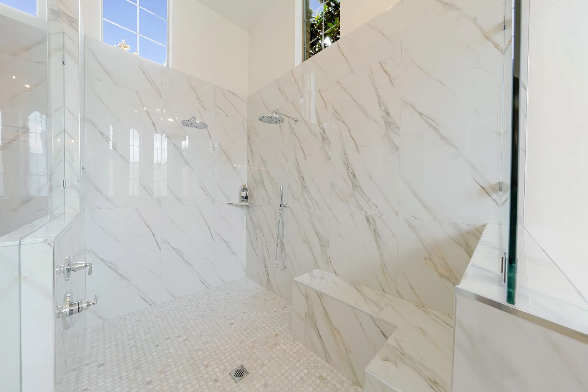 Spacious walk-in shower featuring large format wall tiles with natural veining and hexagonal mosaic floor tiling