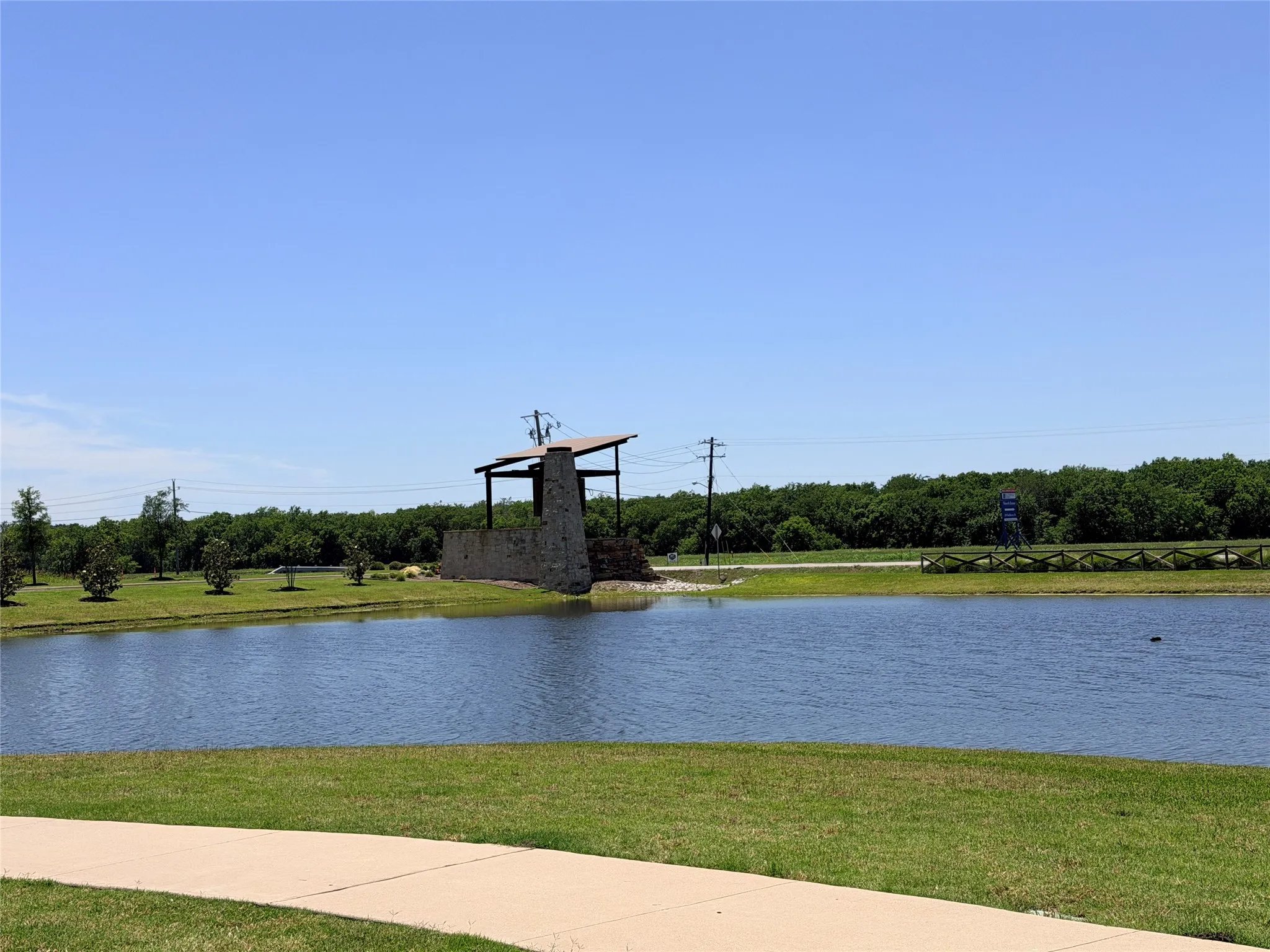 Water feature with a stone structure, framed by green space and a treeline