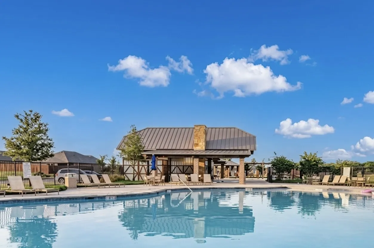 Resort-style pool area featuring a large swimming pool, a covered pavilion with stone accents and a metal roof, and surrounding hardscaping