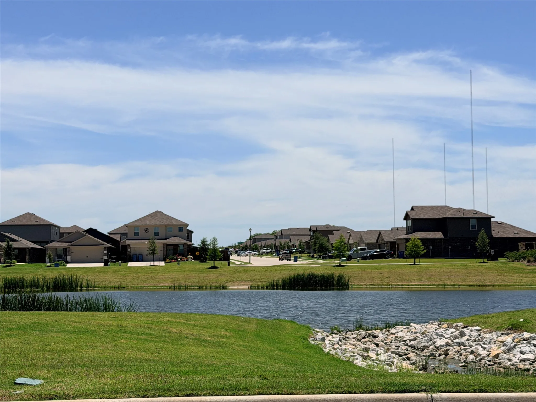Pond with surrounding green space, featuring manicured lawns and scattered trees