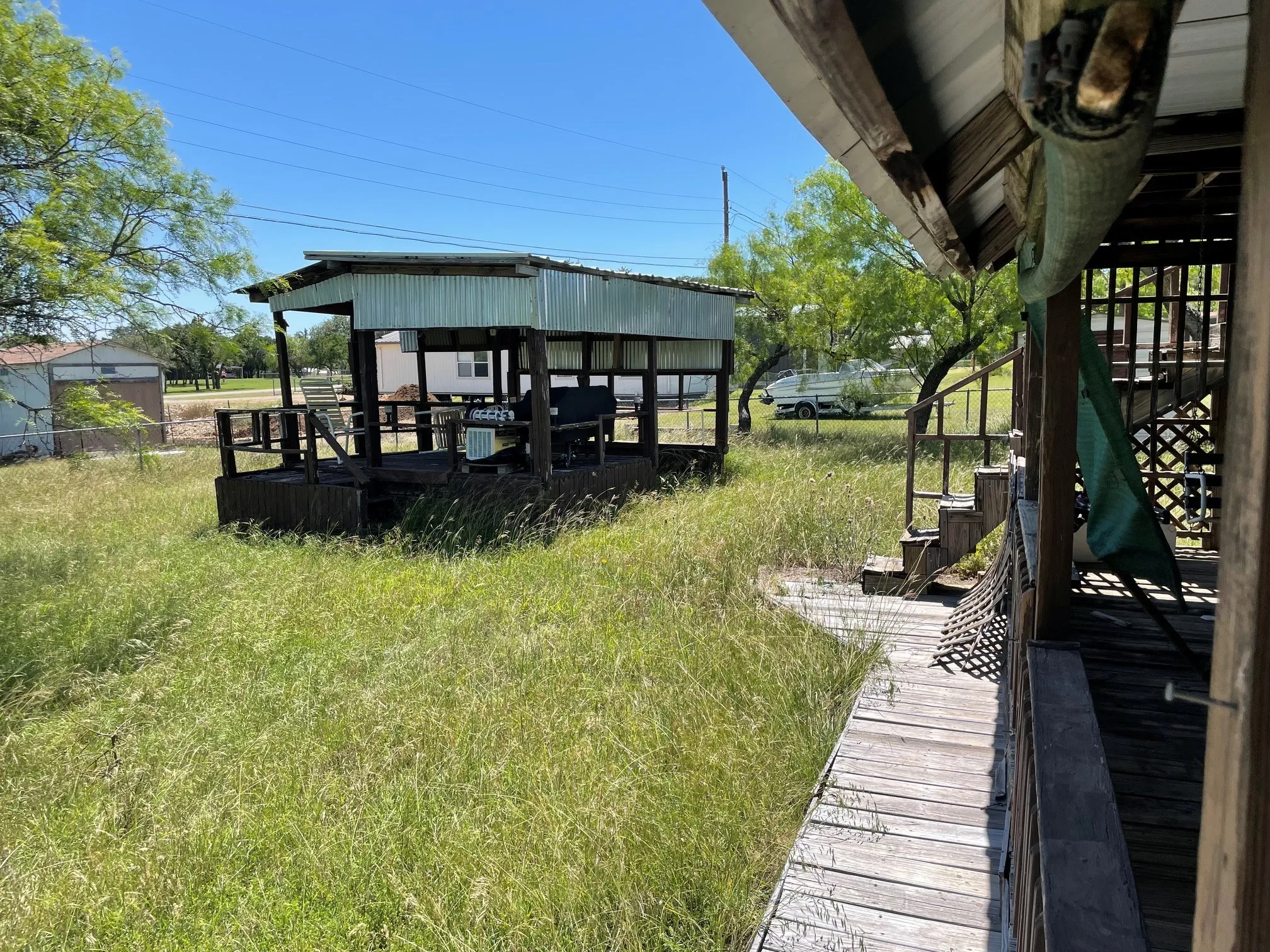 Covered outdoor deck structure with a corrugated metal roof, open railings, and a wooden deck surface