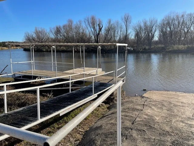 Private dock structure featuring a walkway with non-slip surfacing, a covered platform, and direct water access