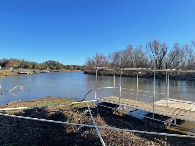 Private boat dock with covered slip, featuring a wood deck surface and metal railing