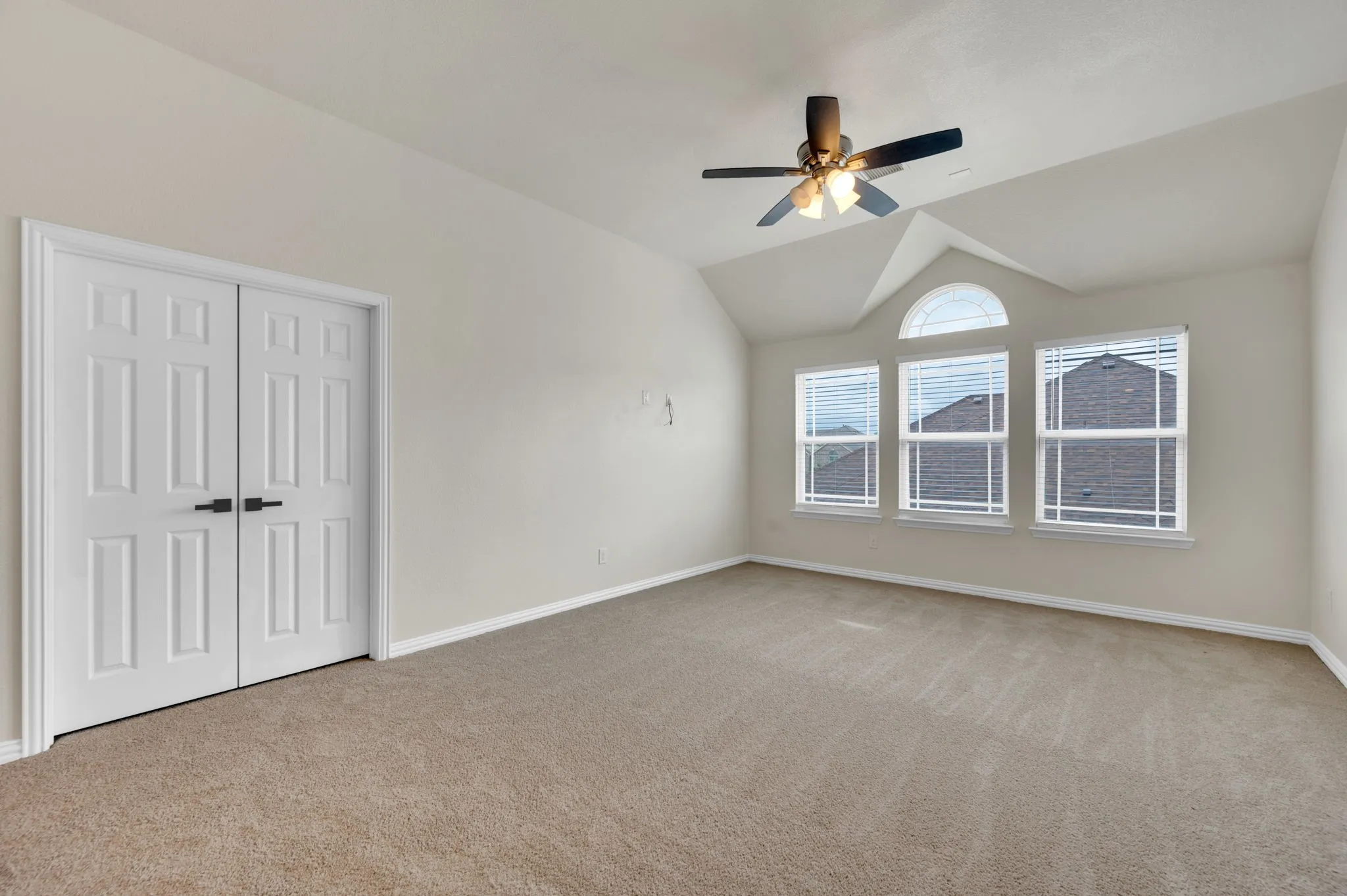 Vaulted ceiling room featuring three windows with blinds and an arched transom window