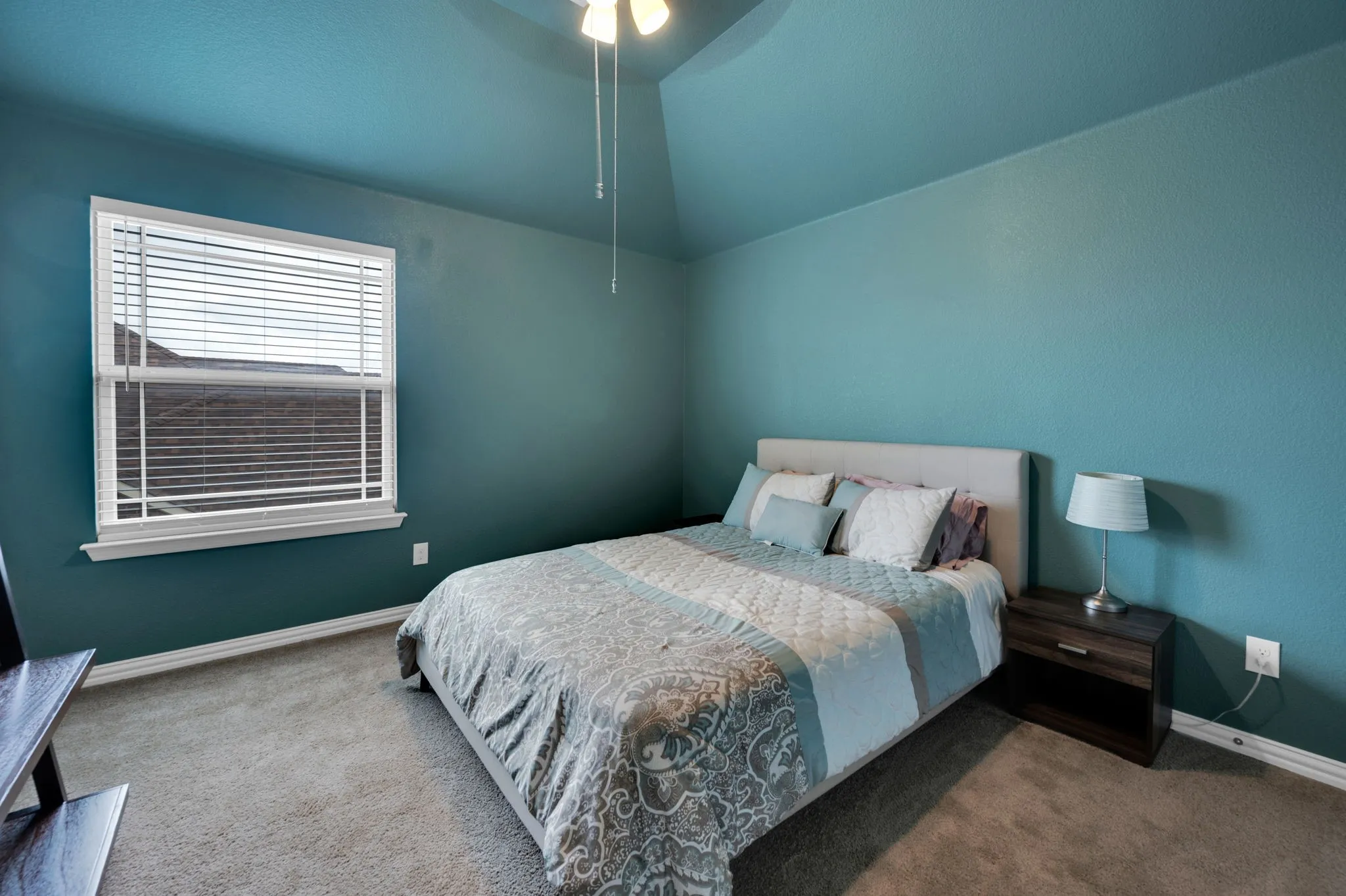 Bedroom featuring a vaulted ceiling with a ceiling fan, wall-to-wall carpeting, and a window with blinds
