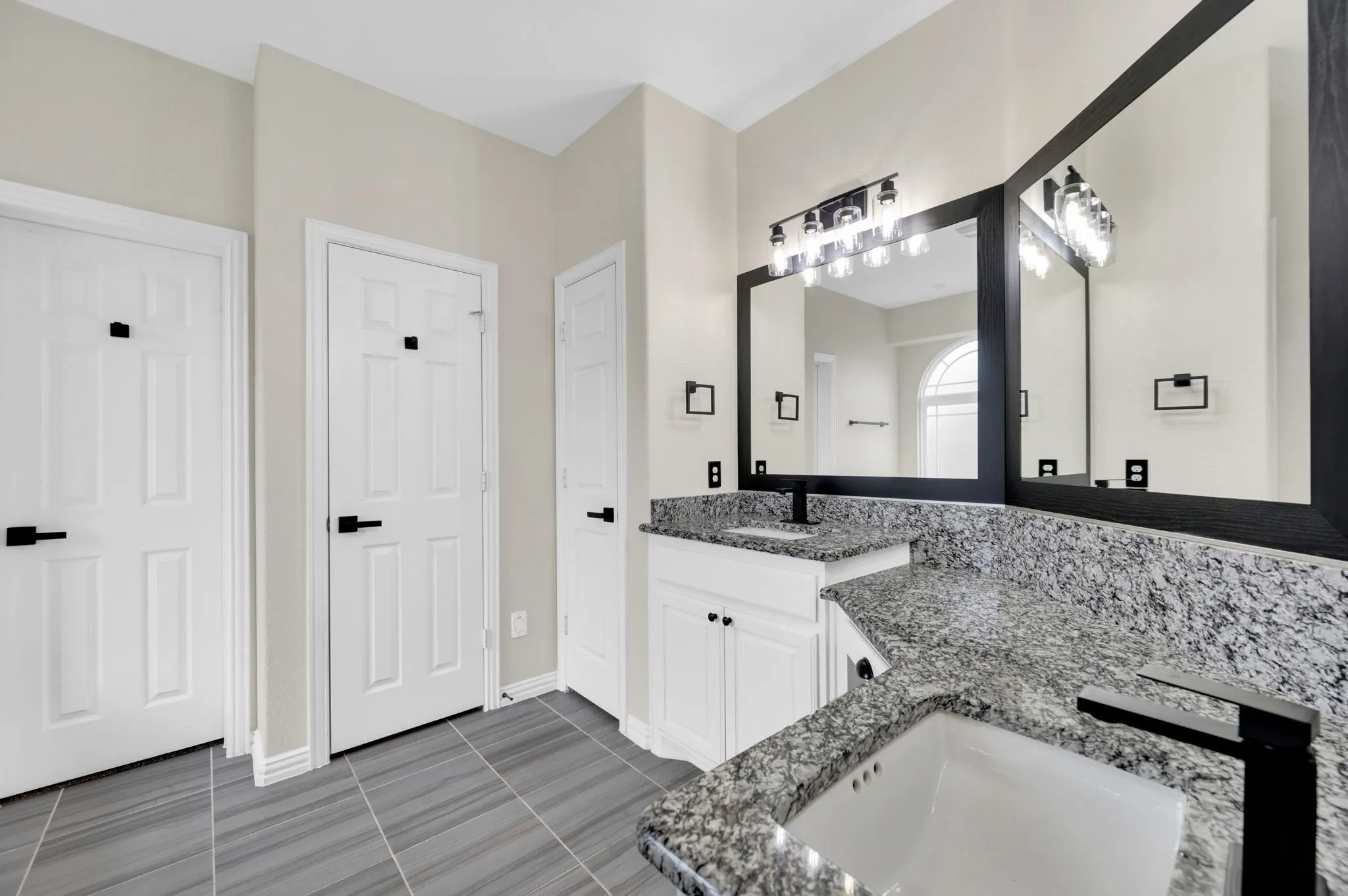 Dual sink vanity featuring granite countertops and white cabinetry