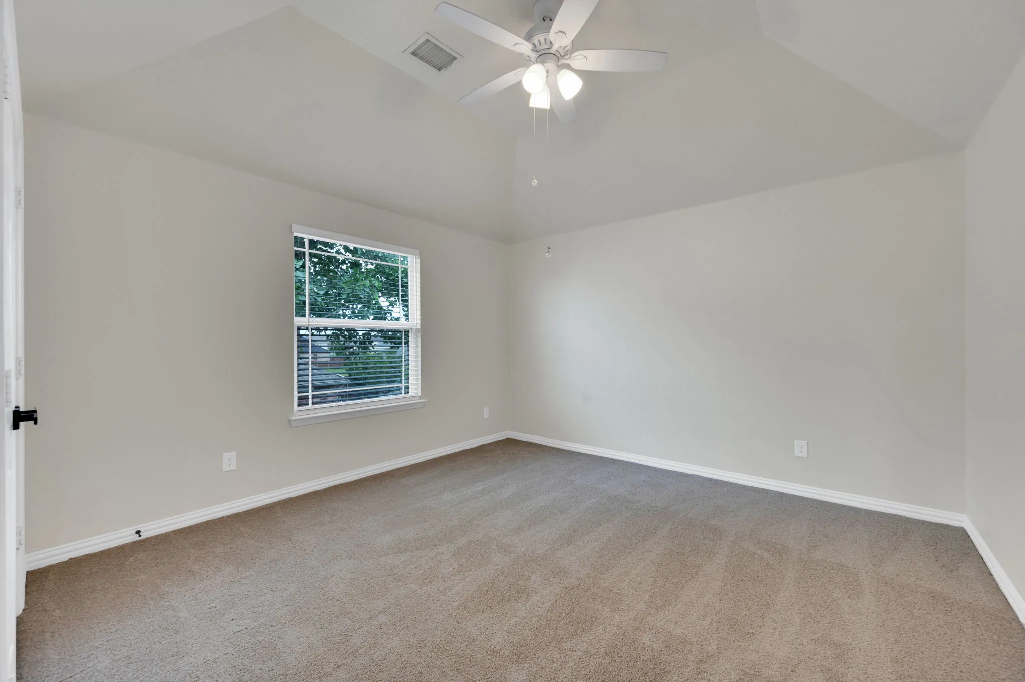 Carpeted room featuring a single window with horizontal blinds, vaulted ceiling, and a ceiling fan with integrated lighting