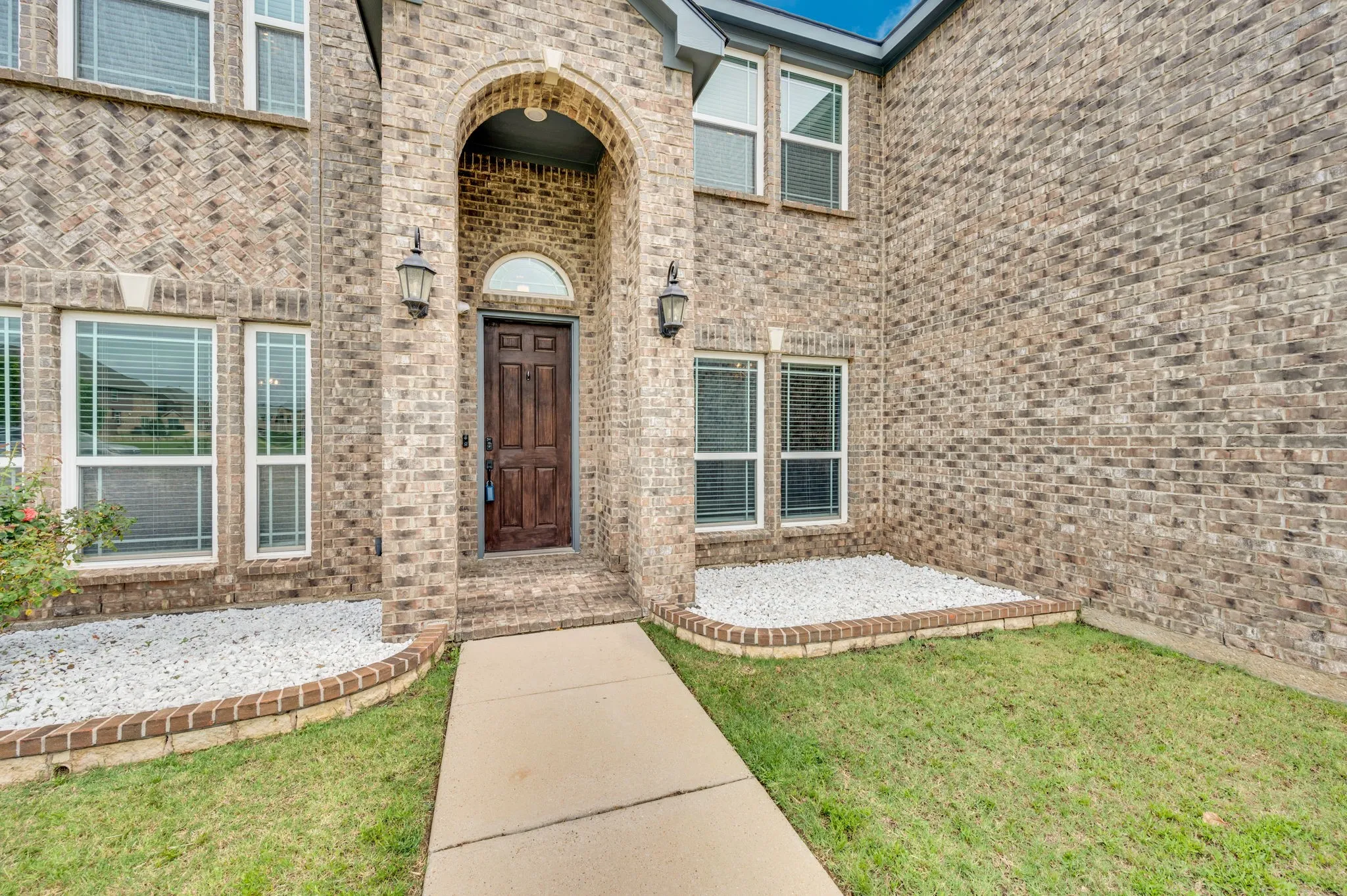 Brick facade residence featuring an arched entryway with a paneled wood door and arched transom window