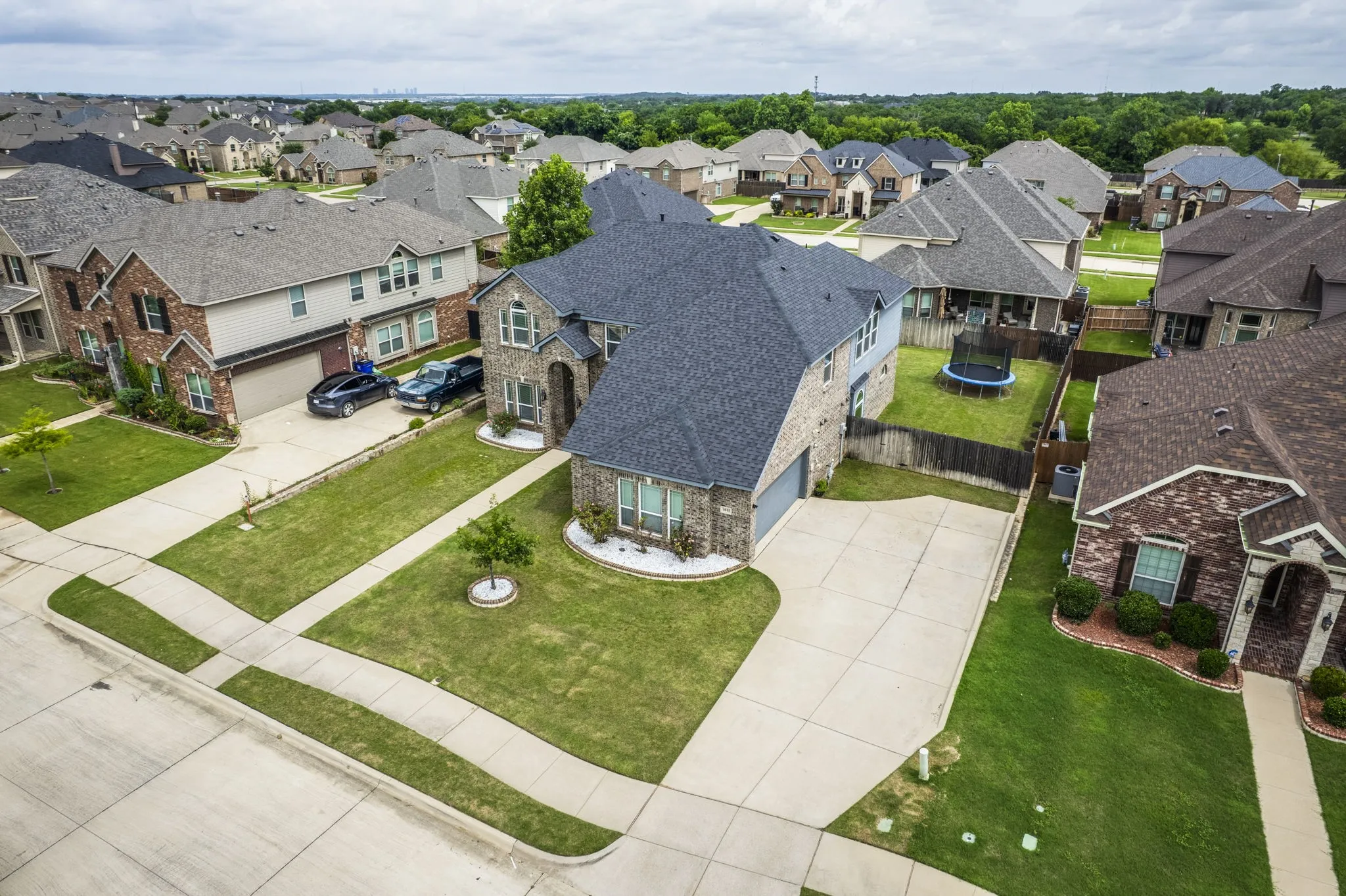 Two-story brick and siding residence featuring a two-car garage, concrete driveway, and manicured front lawn