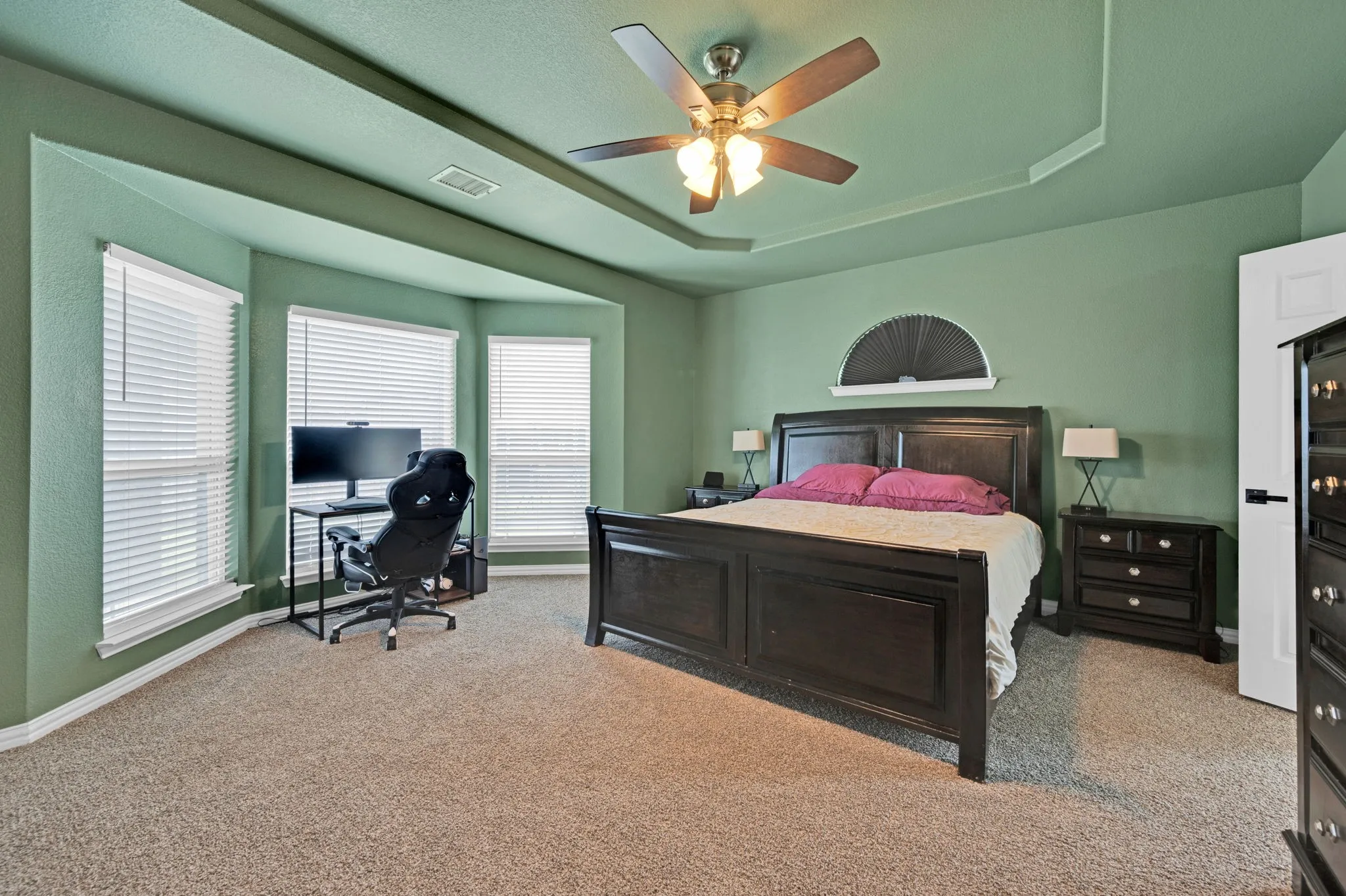 Spacious room featuring a tray ceiling with a ceiling fan, carpet flooring, and a bay window area