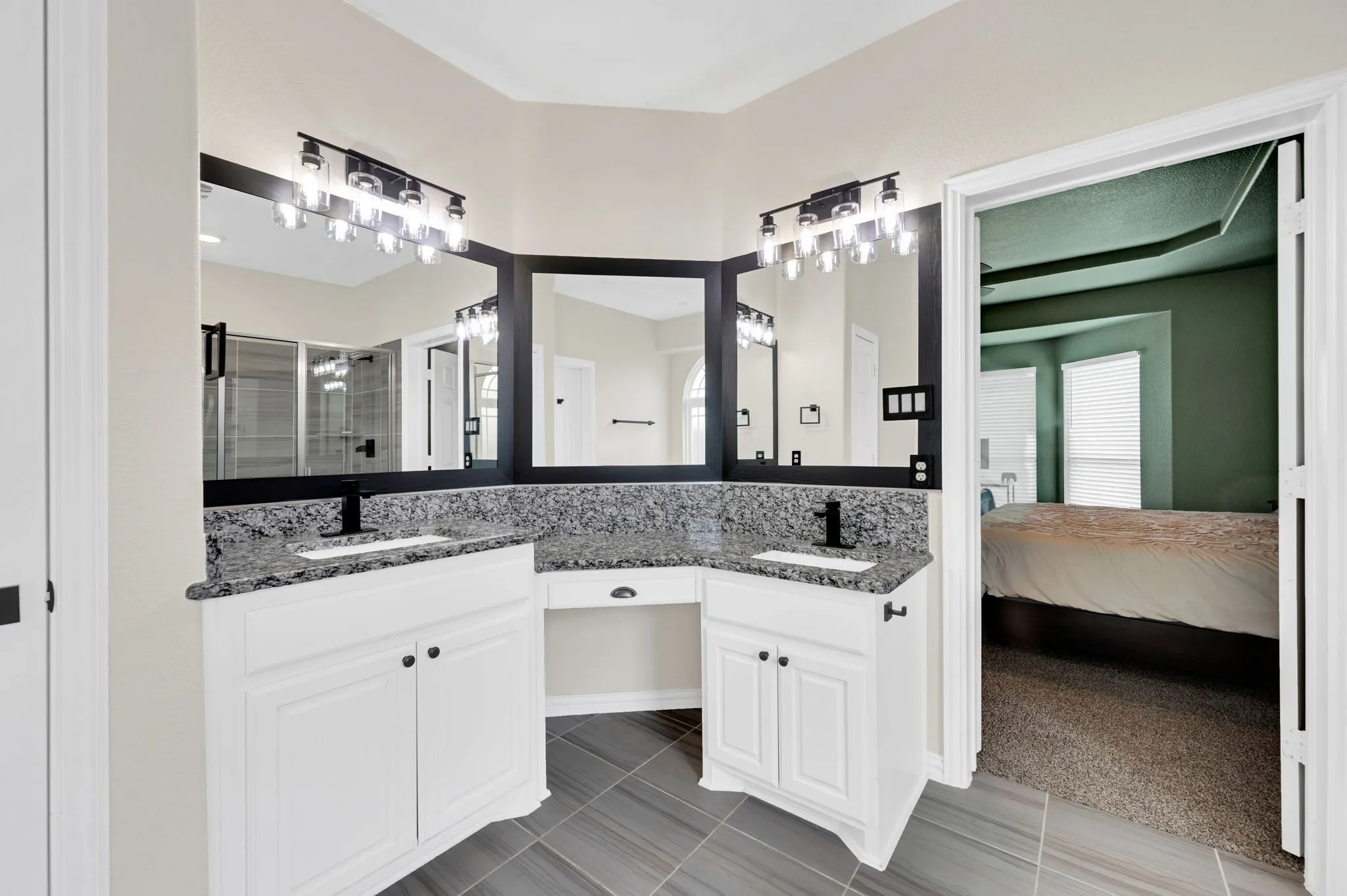 Double vanity with white cabinetry, dark granite countertops, and black fixtures