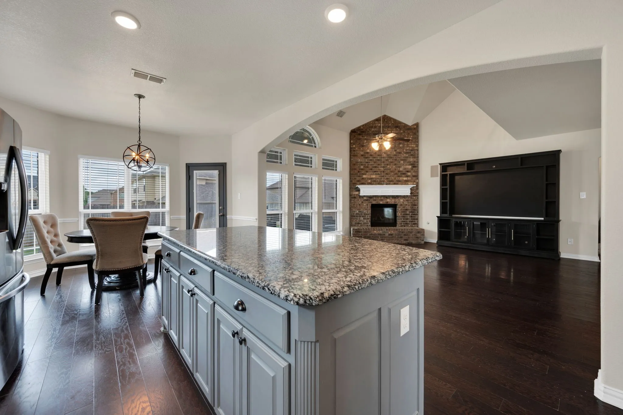 Kitchen island with granite countertop and gray cabinetry