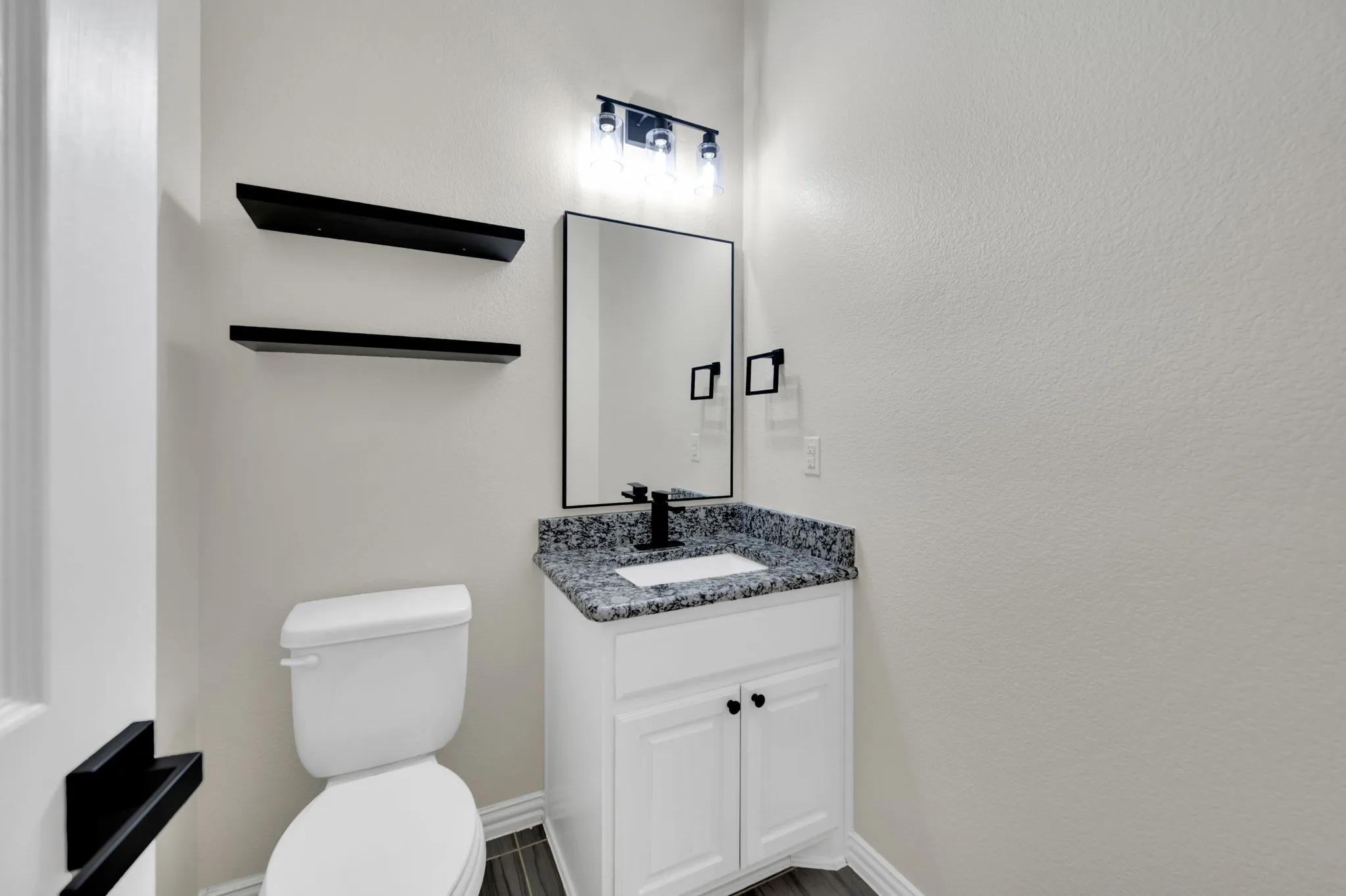 Bathroom featuring a white vanity with dark countertop, undermount sink, and black faucet