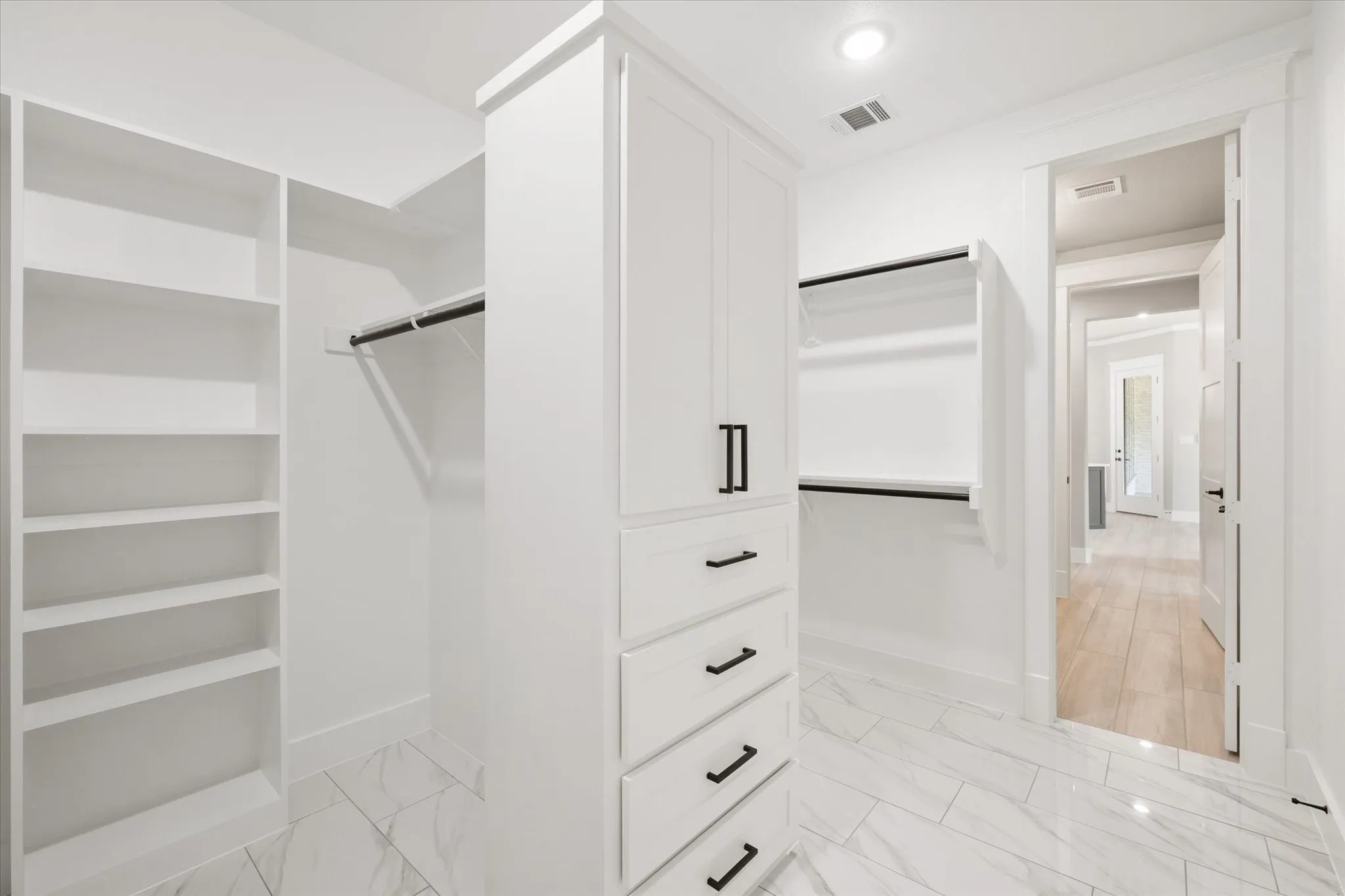 Custom white built-in cabinetry with black hardware, shelving, and hanging rods