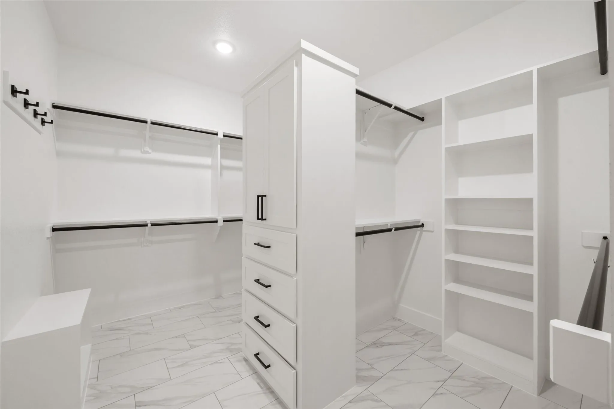 Custom closet system featuring white cabinetry, multiple hanging rods, built-in shelving, and drawer storage