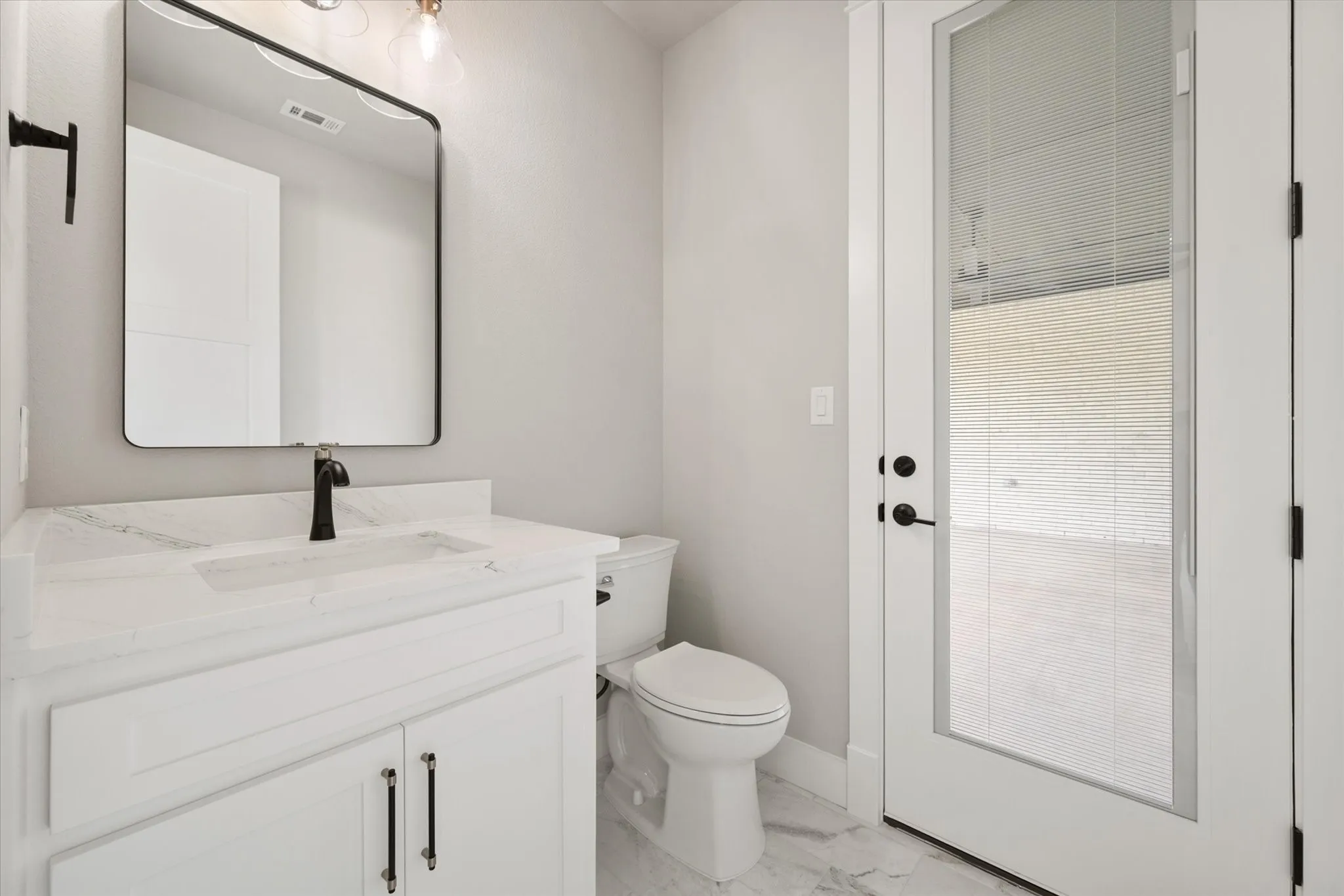 Bathroom featuring a white vanity with a rectangular sink, a black faucet, and a framed mirror