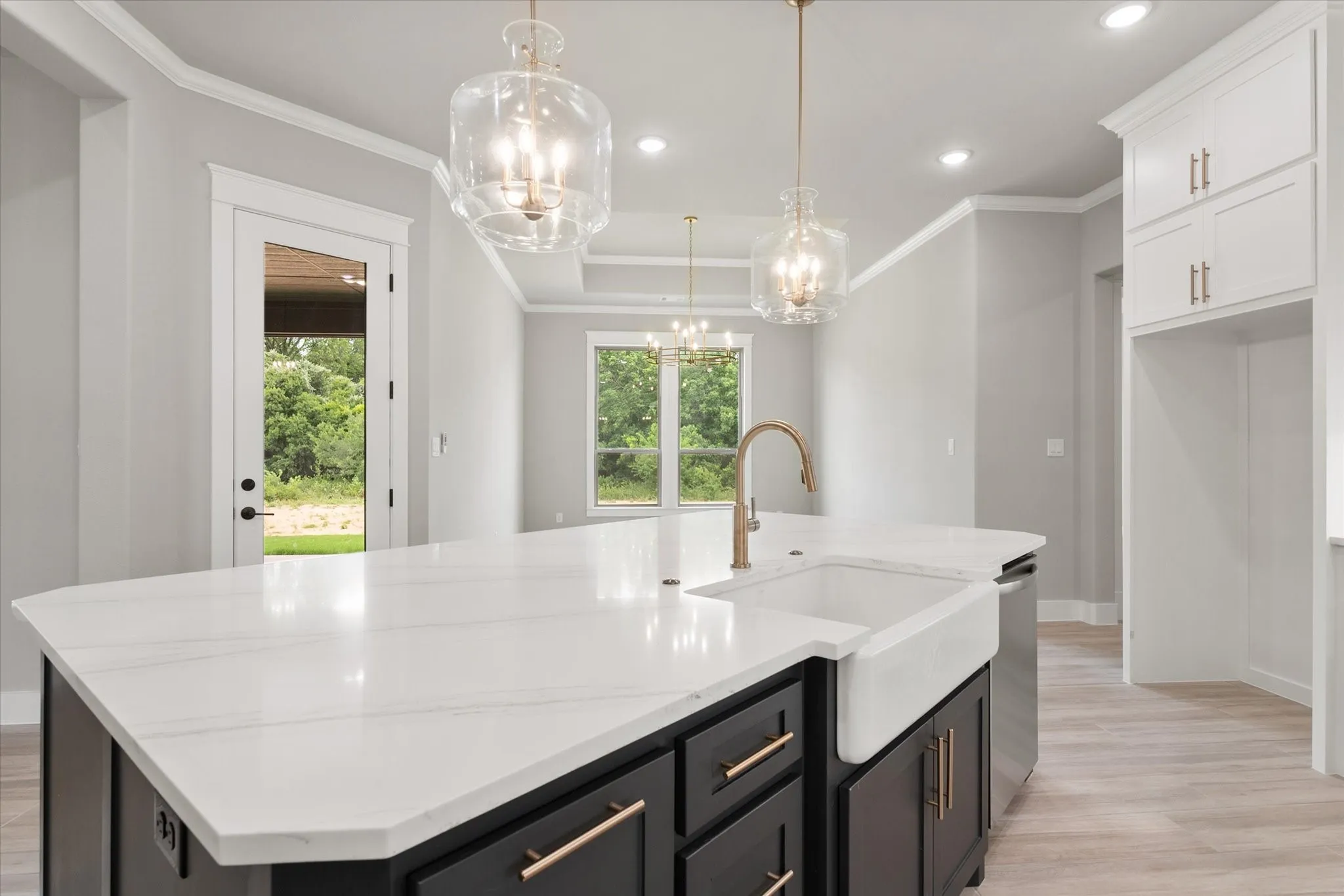 Kitchen island featuring a white apron-front sink, a gold-finish faucet, and a light-toned countertop