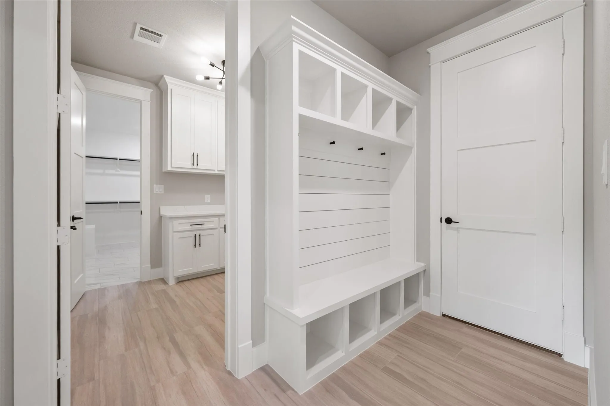 Built-in white mudroom bench with cubby storage, shiplap backing, and coat hooks