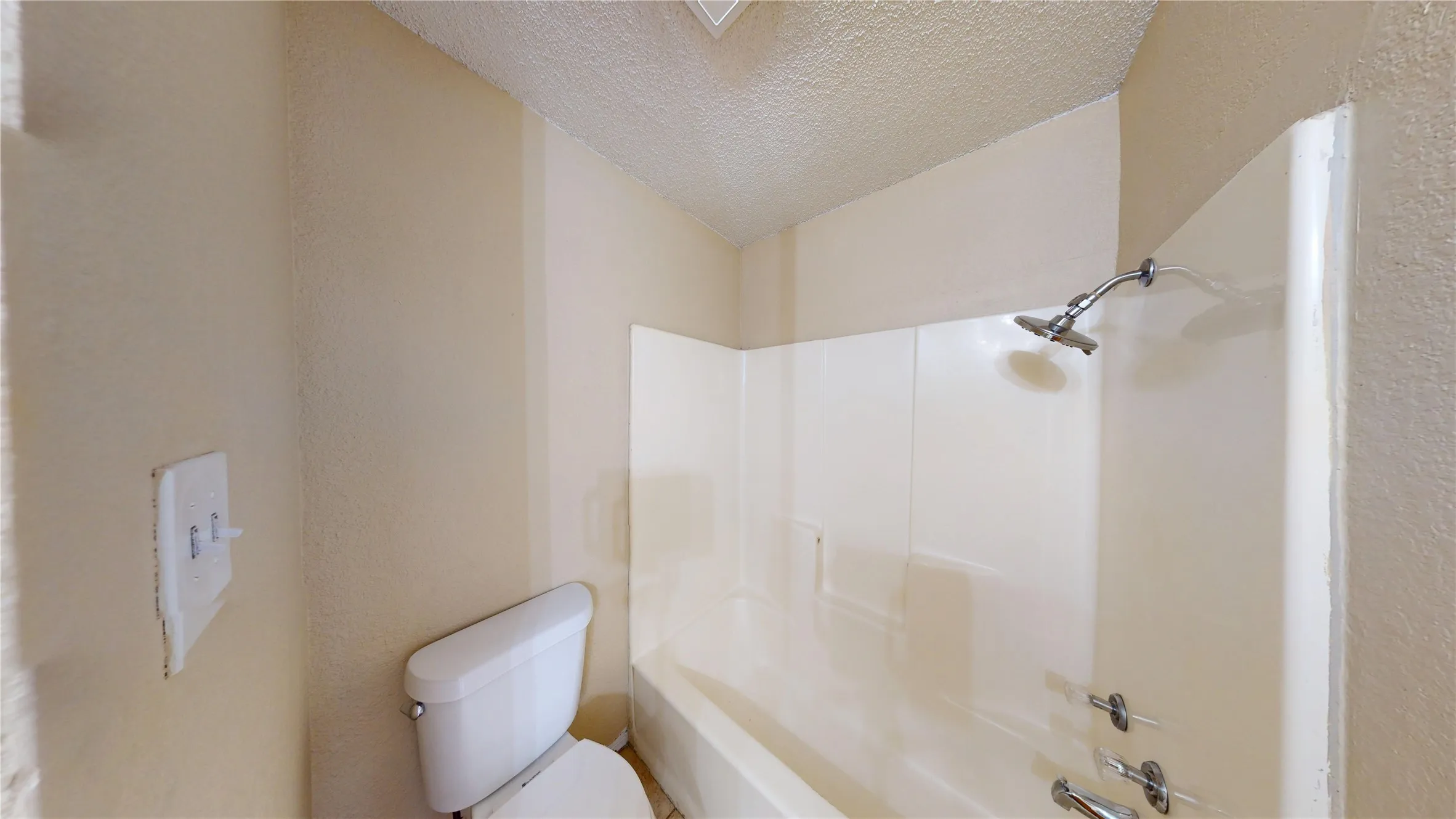 Bathroom featuring a white toilet and a tub with an integrated shower surround