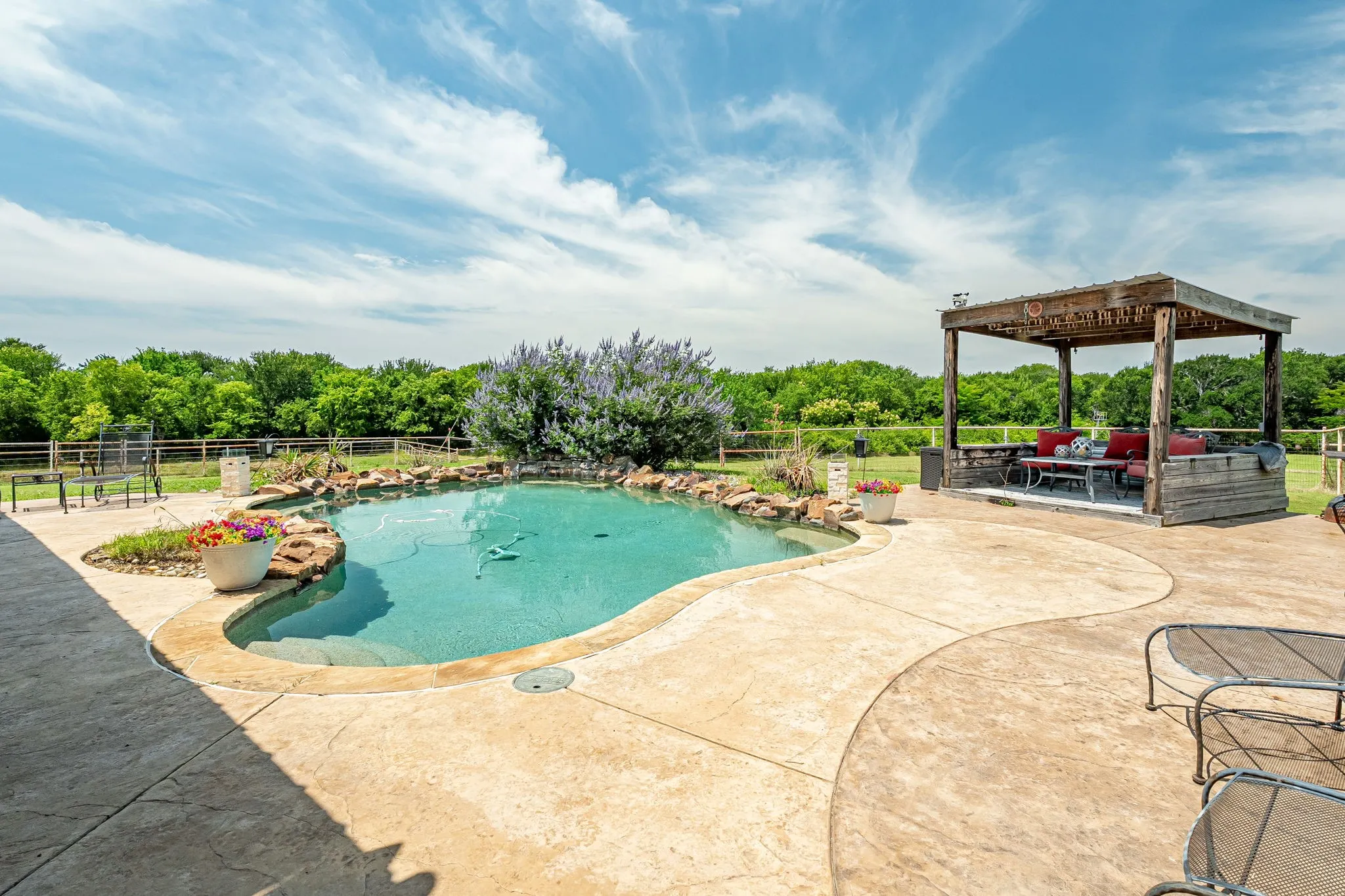Freeform swimming pool with rock detailing, bordered by a concrete patio with stamped accents