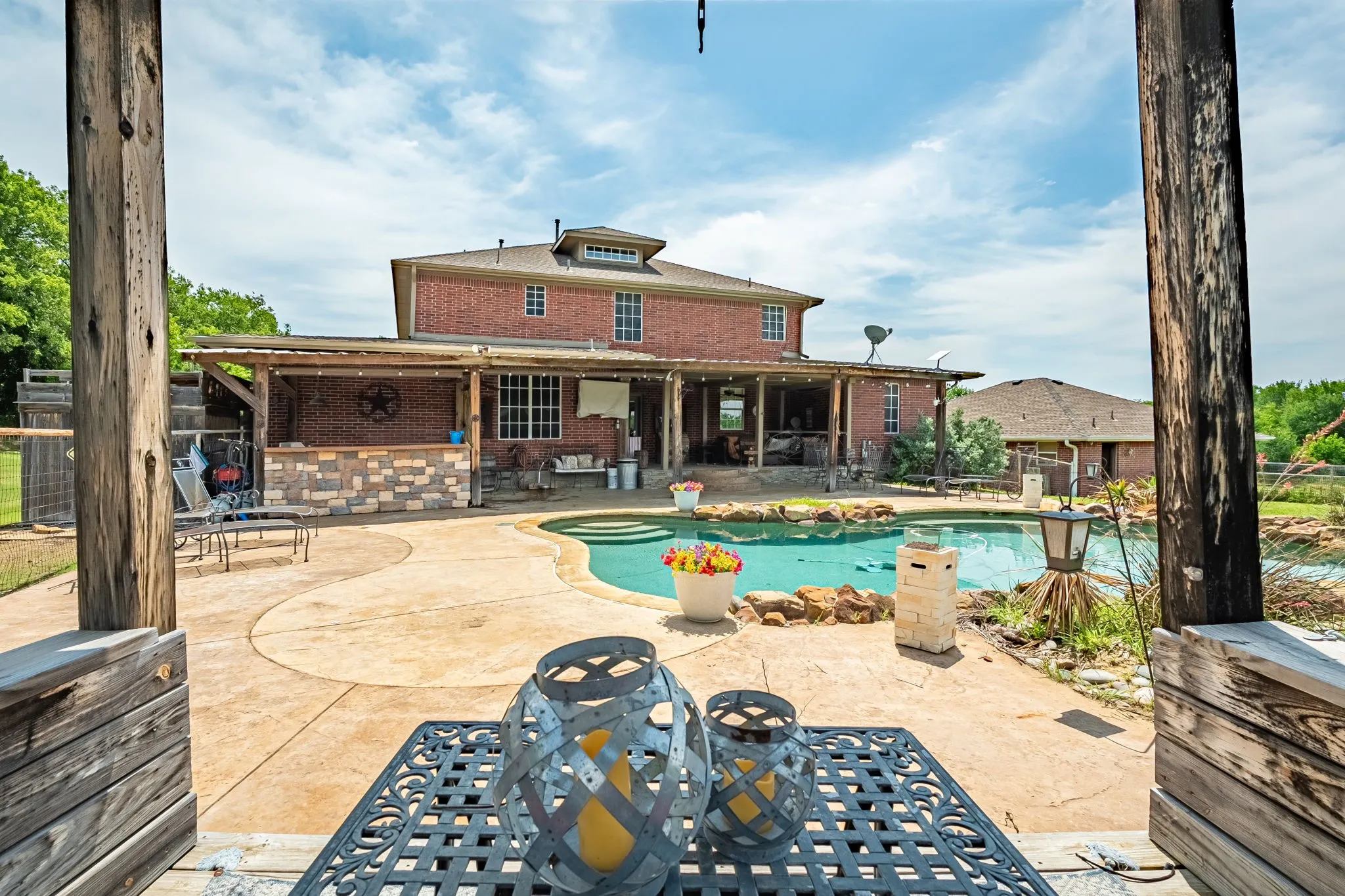 Expansive backyard featuring a freeform swimming pool with rock accents, a stamped concrete patio, and a covered outdoor living area