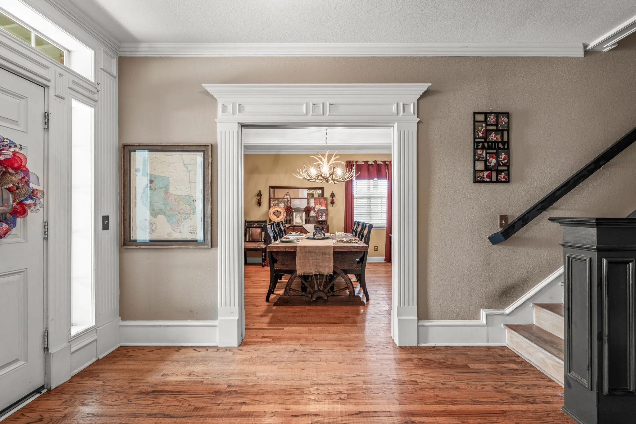 Entryway featuring wood-finish flooring, a white paneled door with sidelights, and an interior archway with fluted trim and crown molding