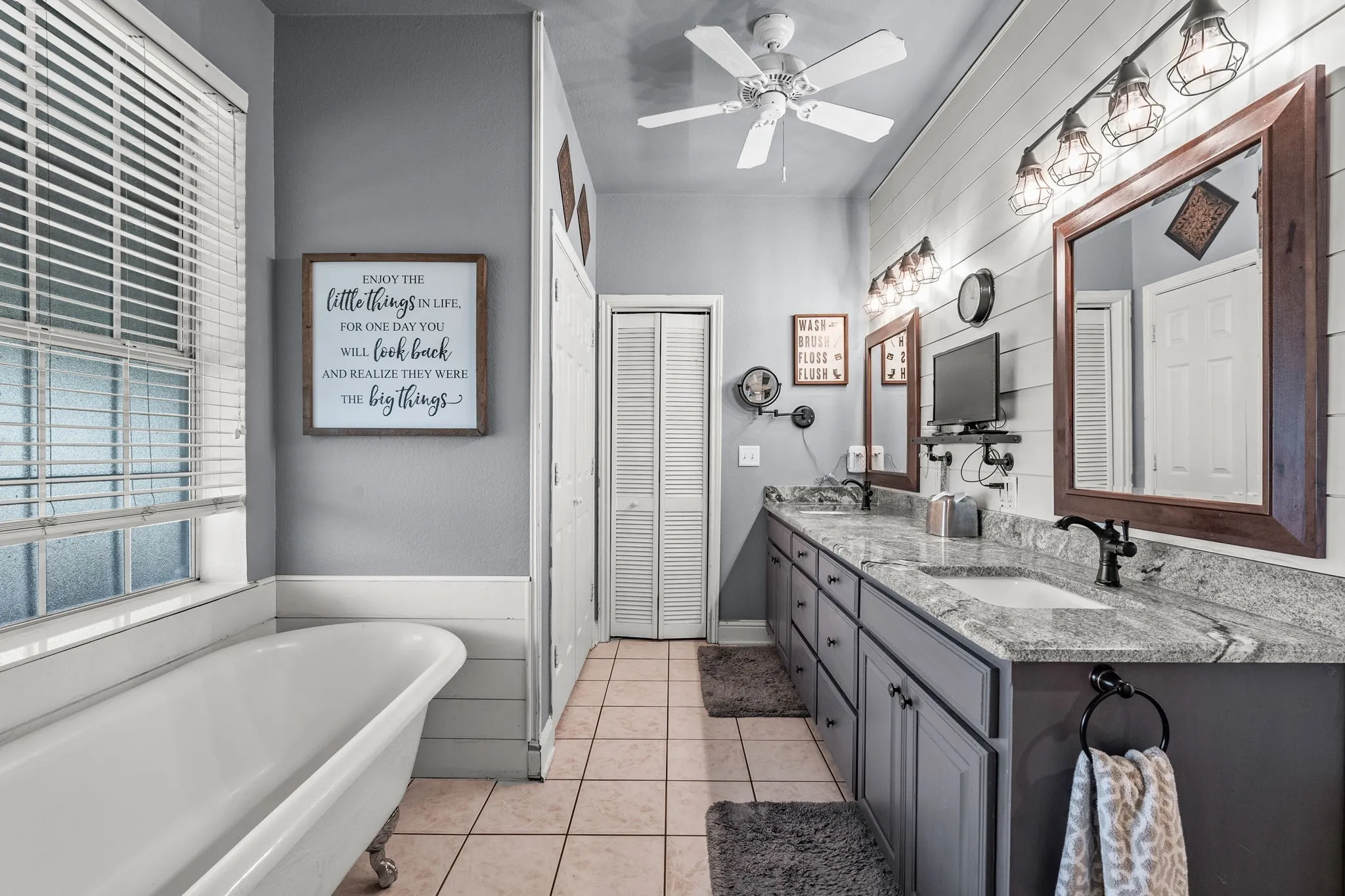 Bathroom featuring a freestanding clawfoot tub, dual vanity with granite countertops, and tile flooring