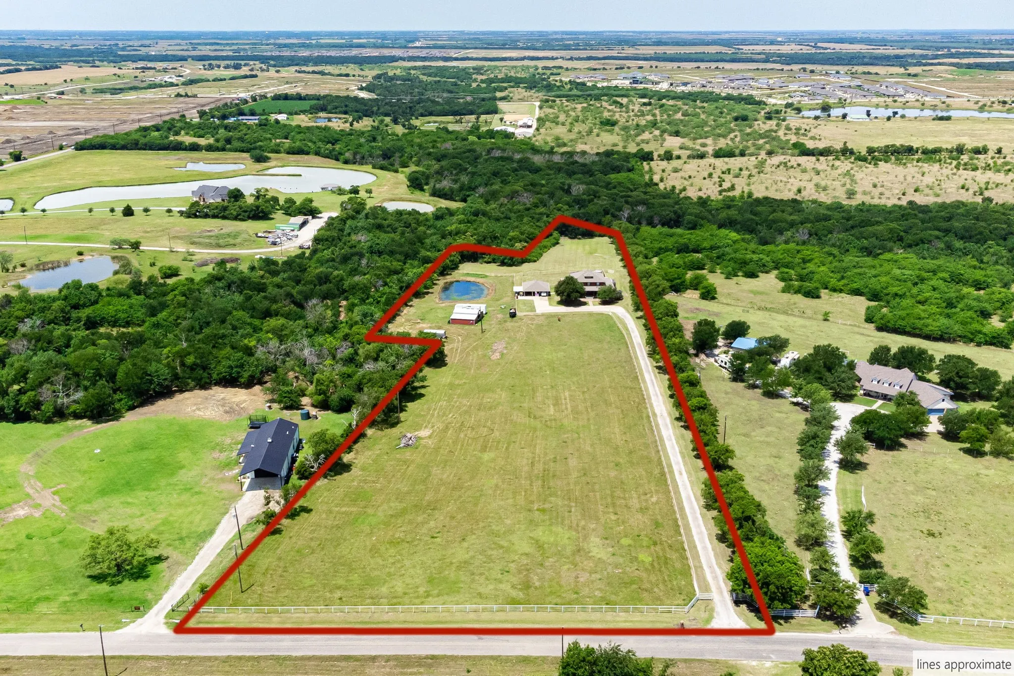 Expansive land parcel featuring a main residence, a secondary building, a pond, and a long private driveway
