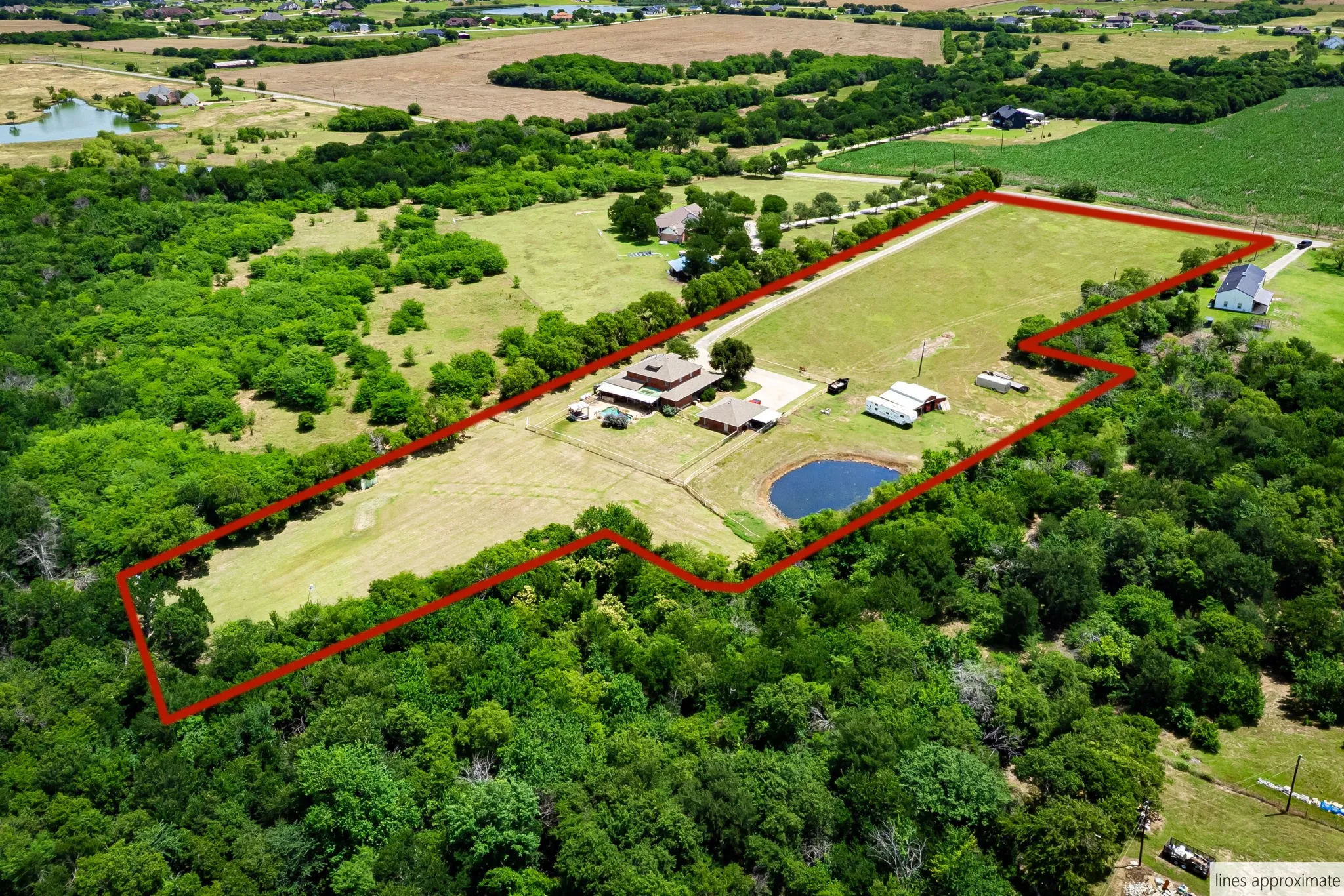Expansive rural property featuring a primary residence, ancillary buildings, a pond, and a combination of wooded and open land