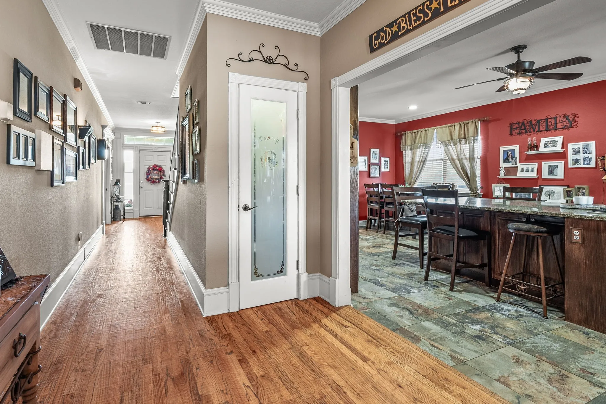 Hardwood flooring extending through the hallway, featuring crown molding and white baseboards