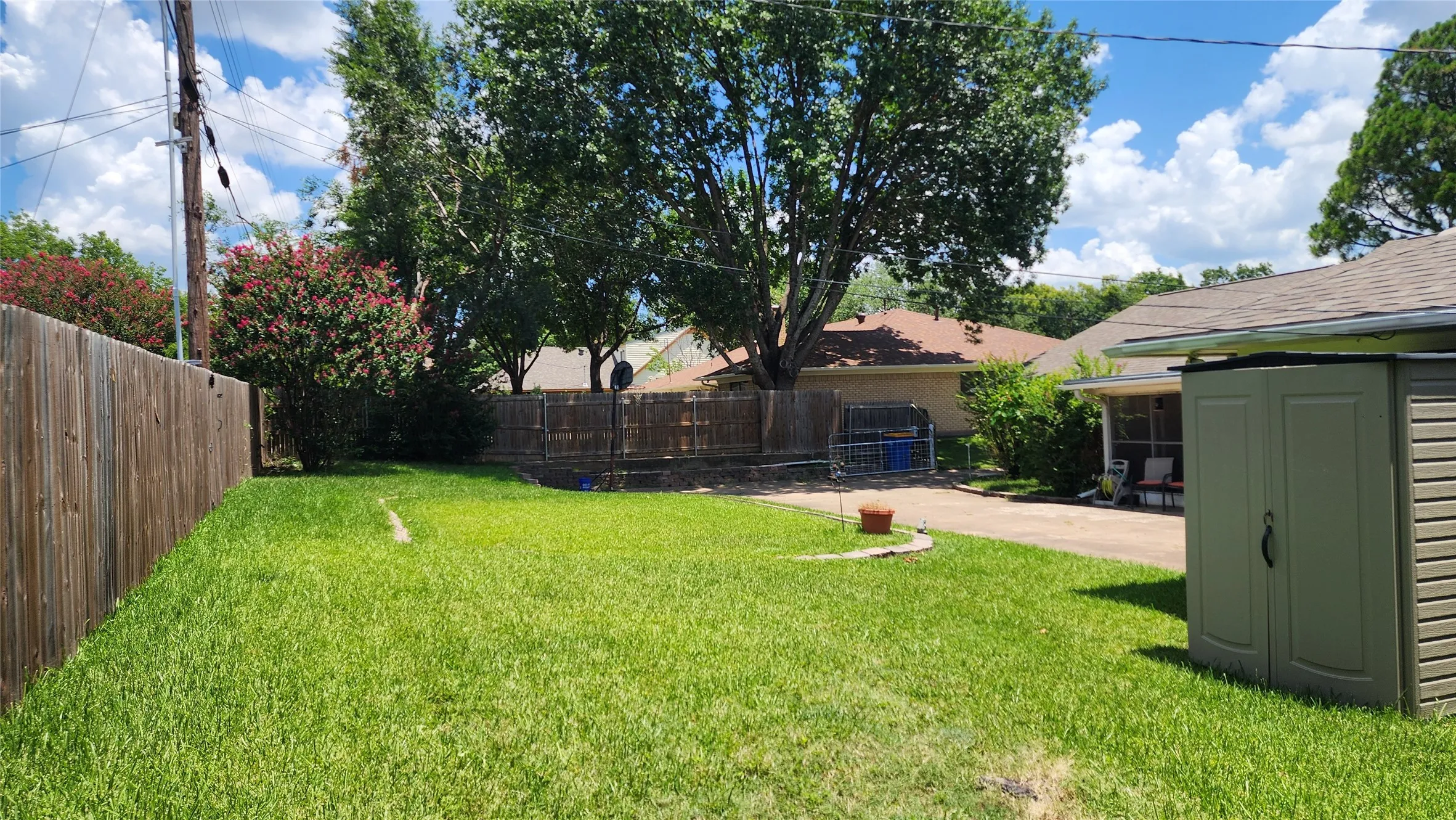 Expansive grassy lawn bordered by a wood fence and mature trees